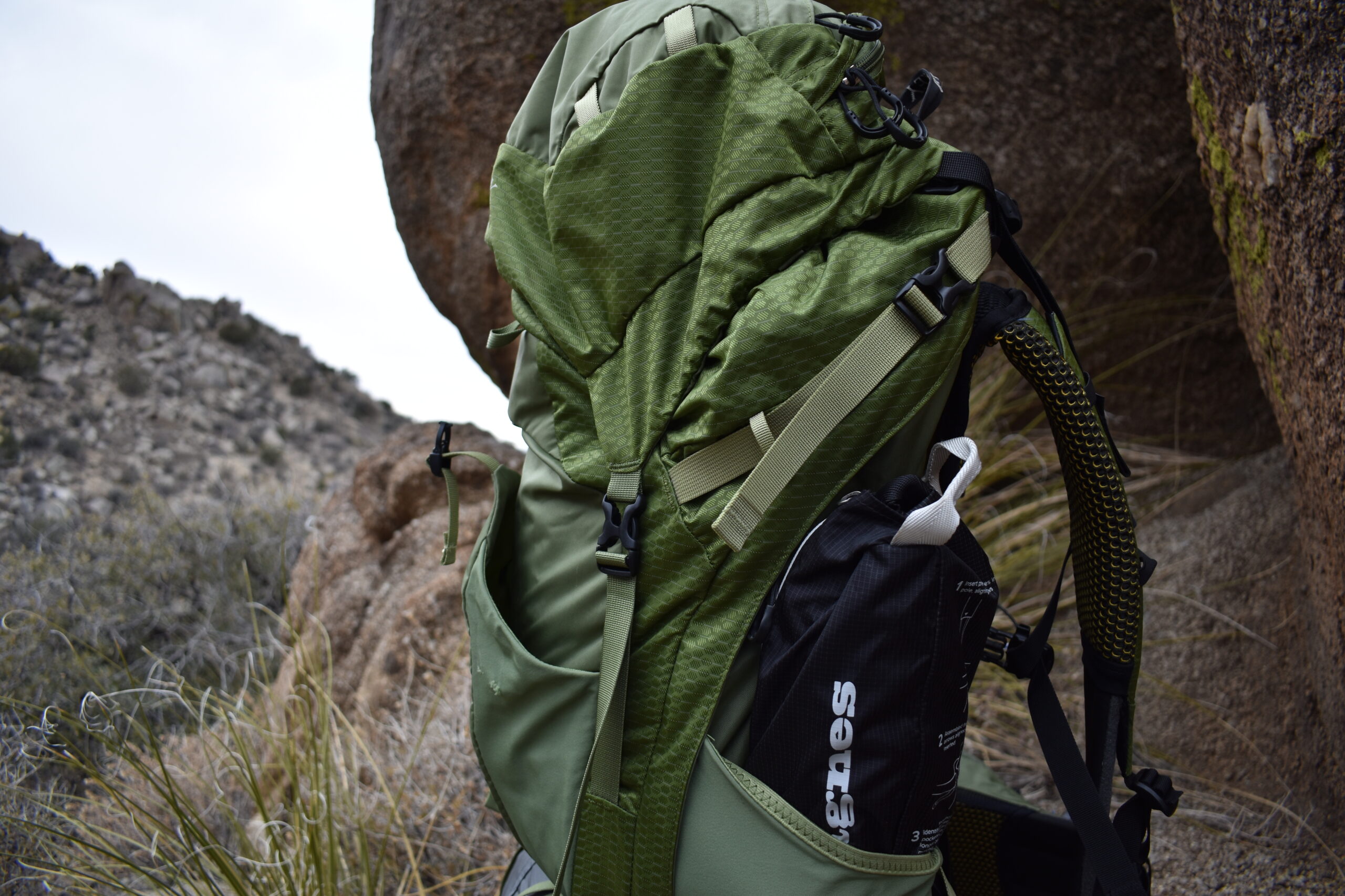 Close up of a backpack with the packed Skyline Chair stuck in its expandable side pockets.