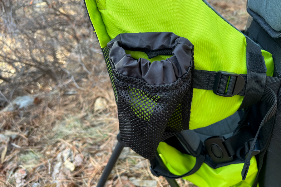 Close-up of a mesh bottle holder with a drawstring closure on the side of a bright green child carrier.