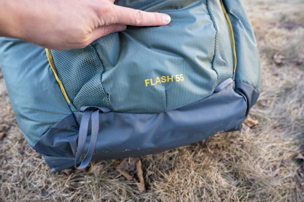 a hand holds the bottom part of a backpack