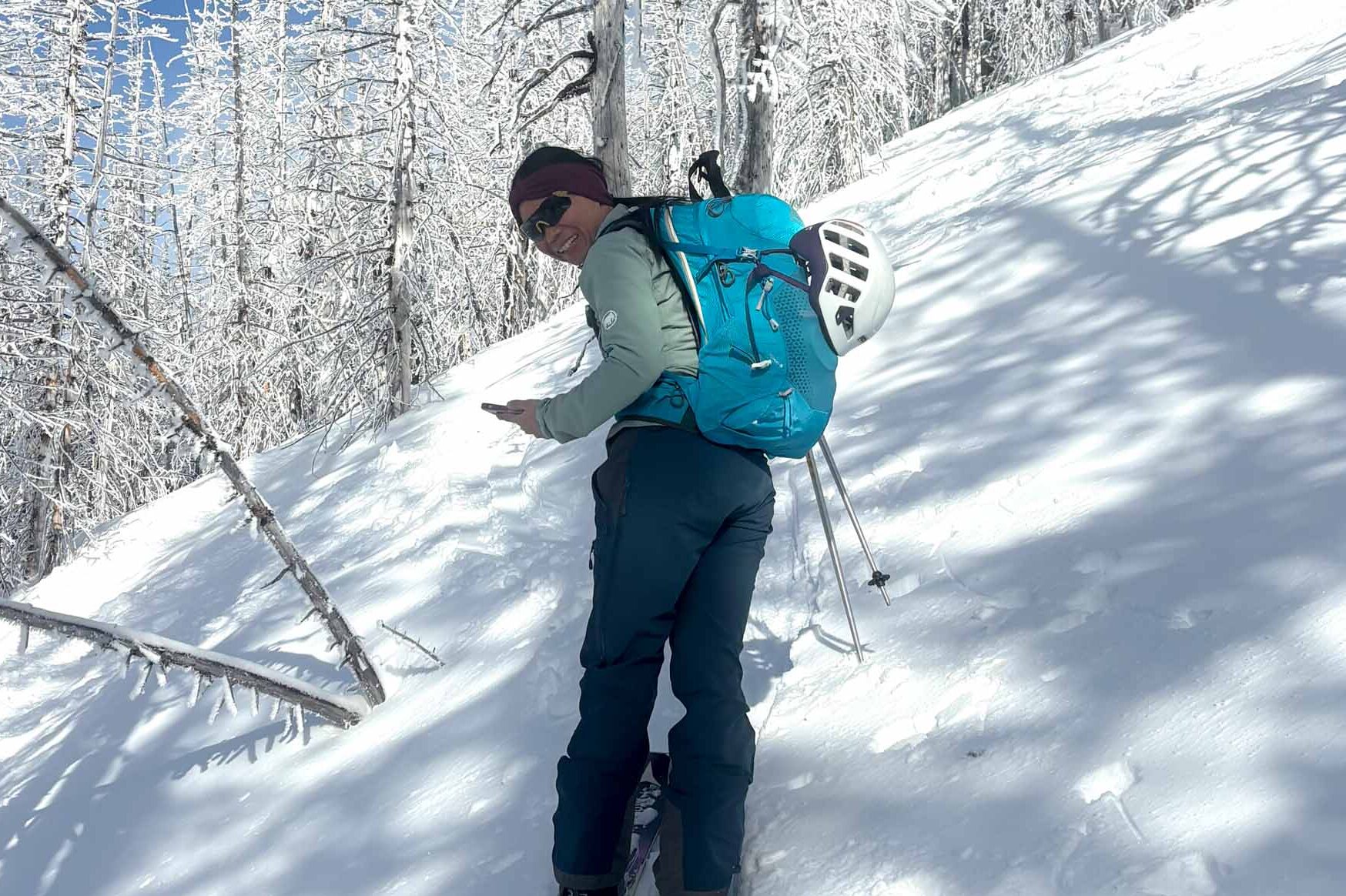 Gregory Juno 24 H2O pack used by a person on skis against a snowy hill with snowy trees on a sunny day