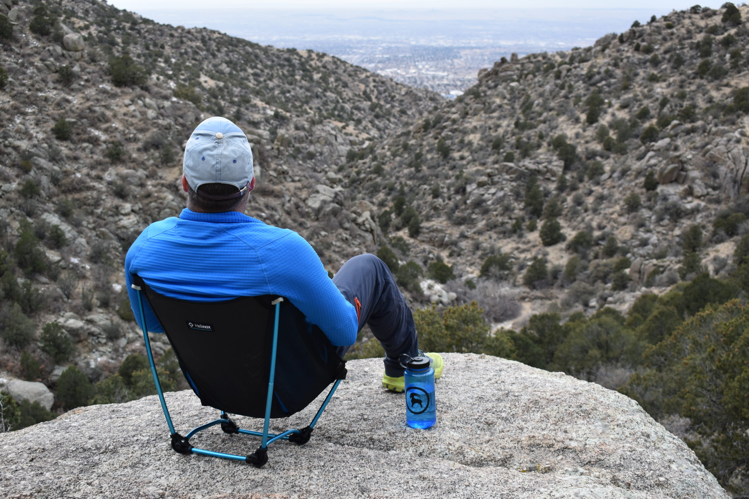 Hiker overlooking a desert canyon while sitting on the Helinox Ground Chair on the edge of a cliff