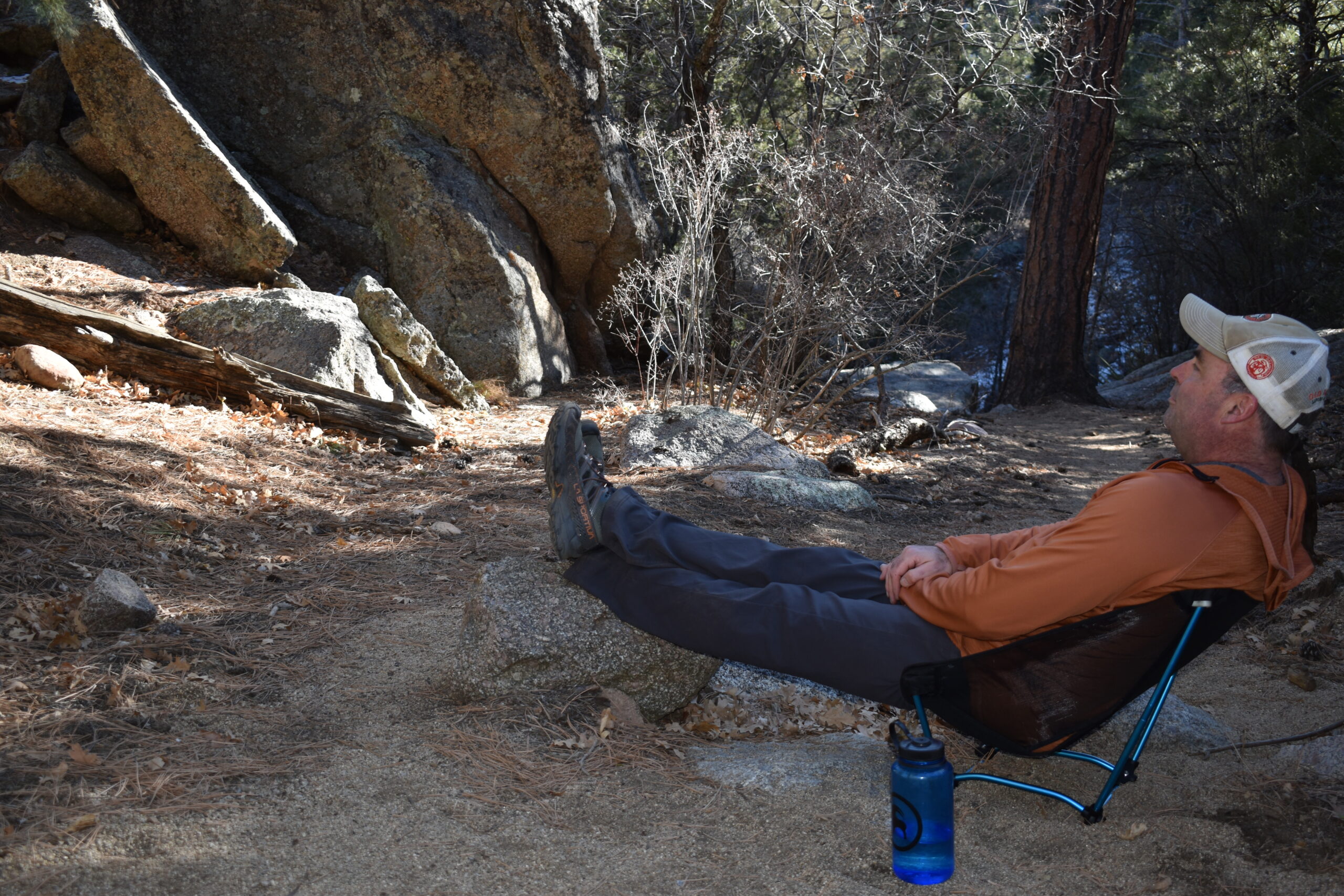 Male hiker leaning back with his legs elevated on a rock while sitting on the Helinox Ground Chair in a canyon campsite