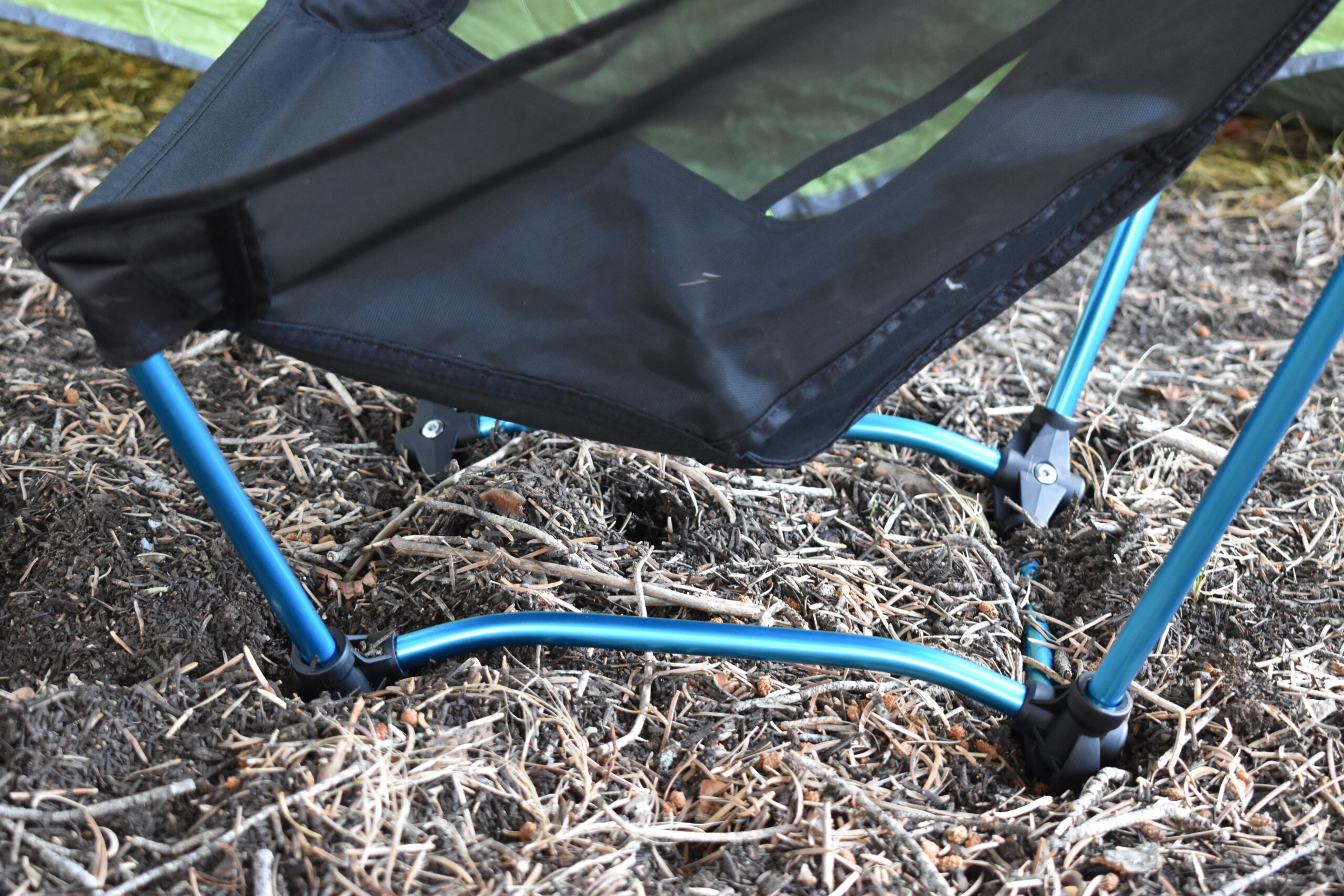 Close up of the square-shaped aluminum frame and feet of the Helinox Ground Chair setting on a soft bed of pine needles