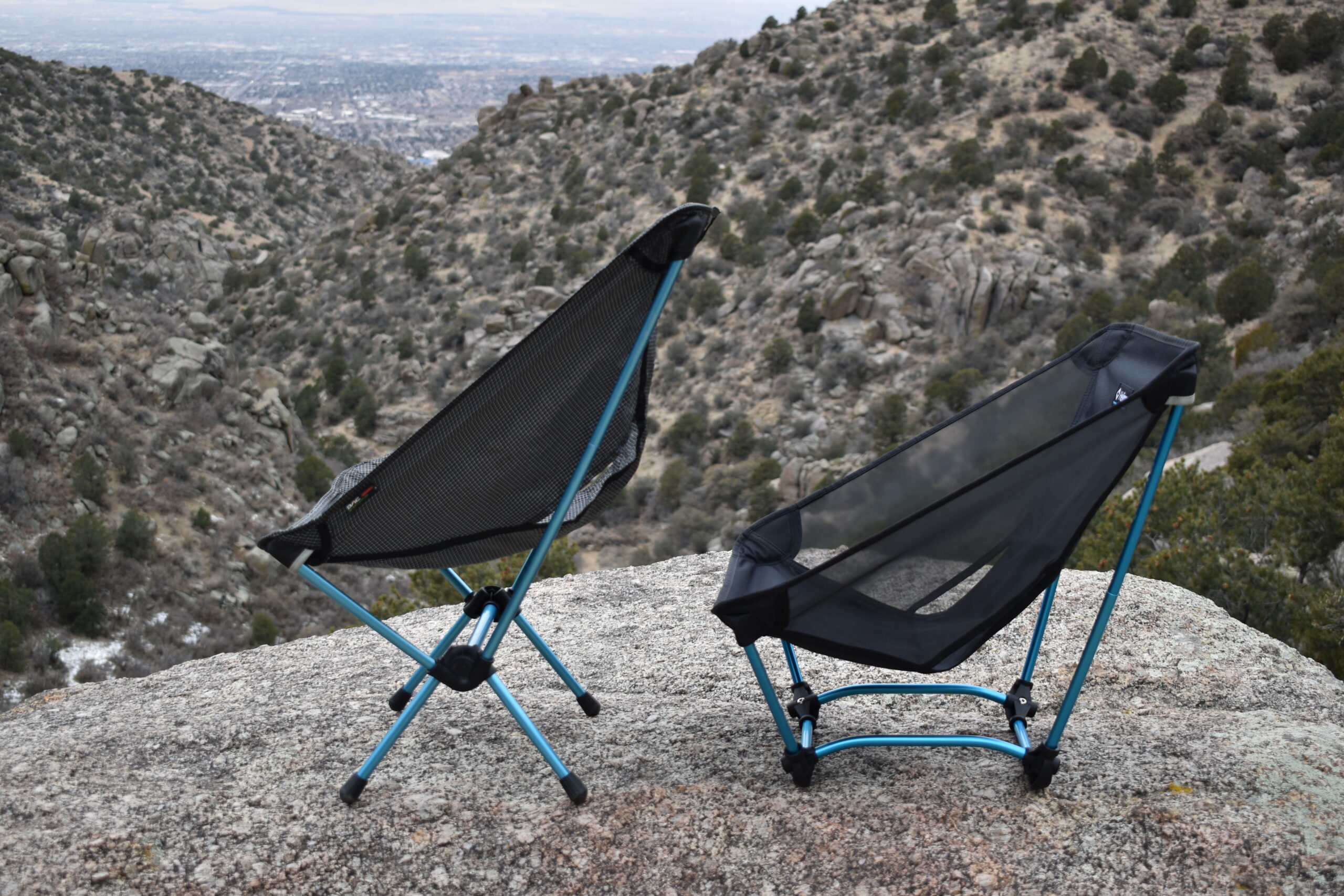 The Helinox Chair Zero and Helinox Ground chair sit side by side on a rocky outcrop to compare their seating positions