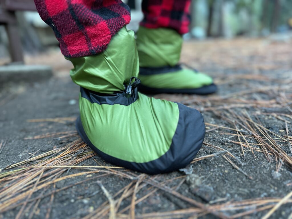 showing off the cinches and adjustments on the green Feathered Friends Down Booties have