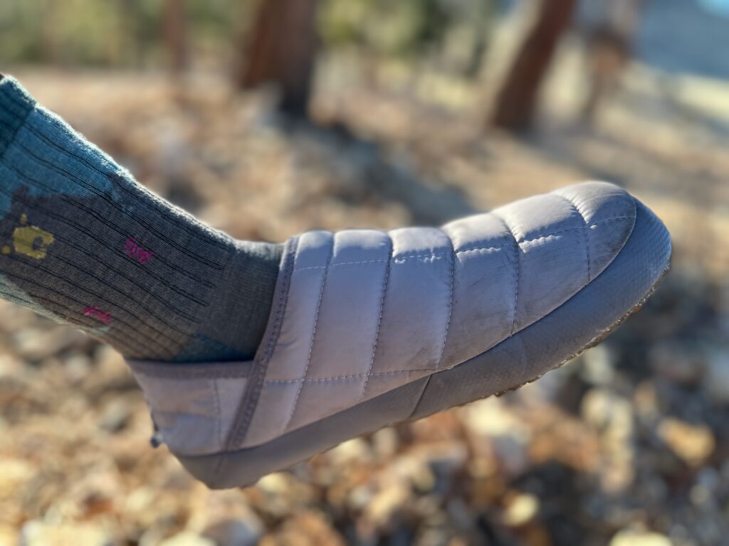 Women showing off North Face ThermoBall Traction Mules V on rocky, high desert camp site