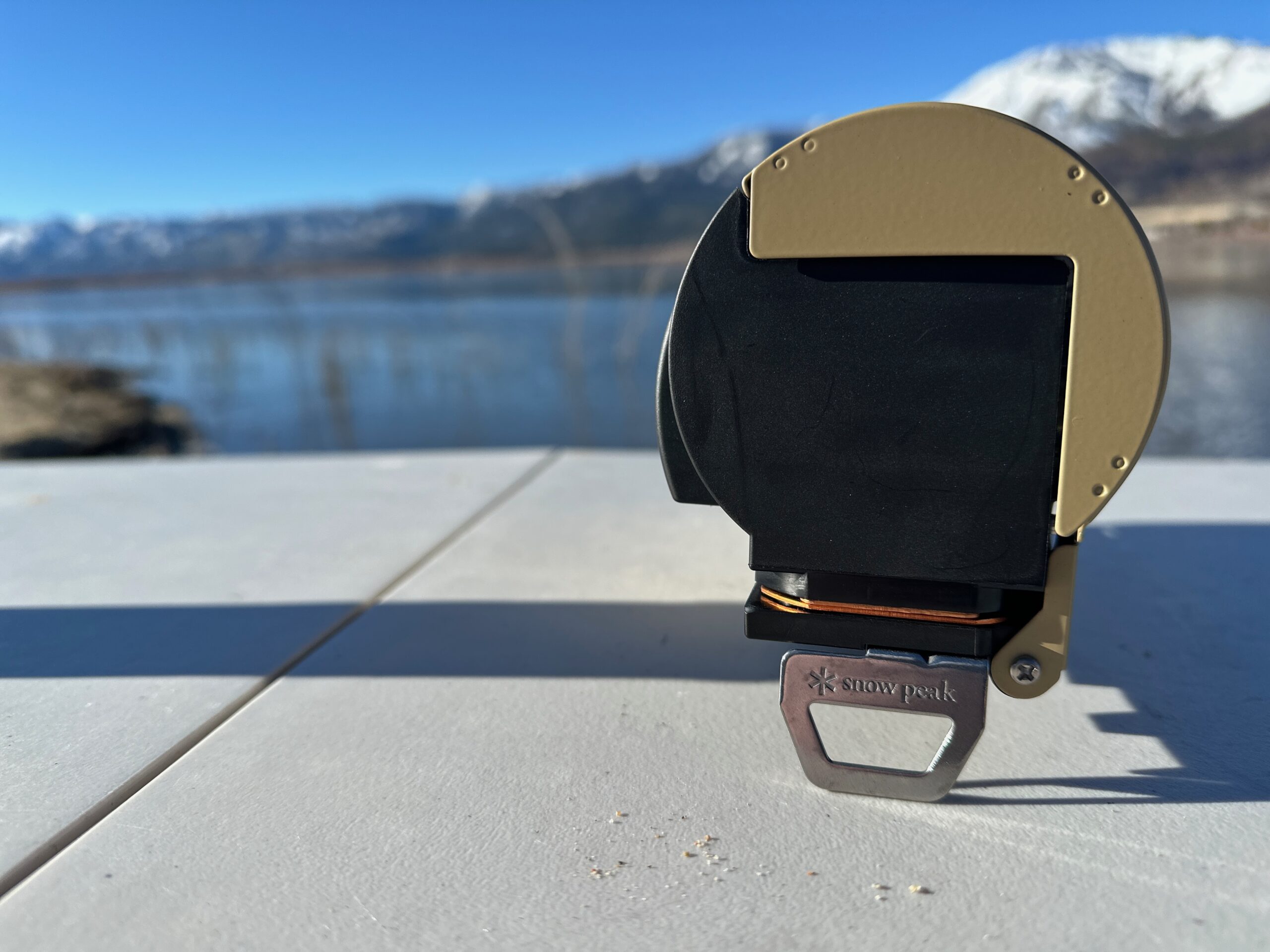 the Snow Peak Home & Camp butane stove folded up on a picnic table at the beach