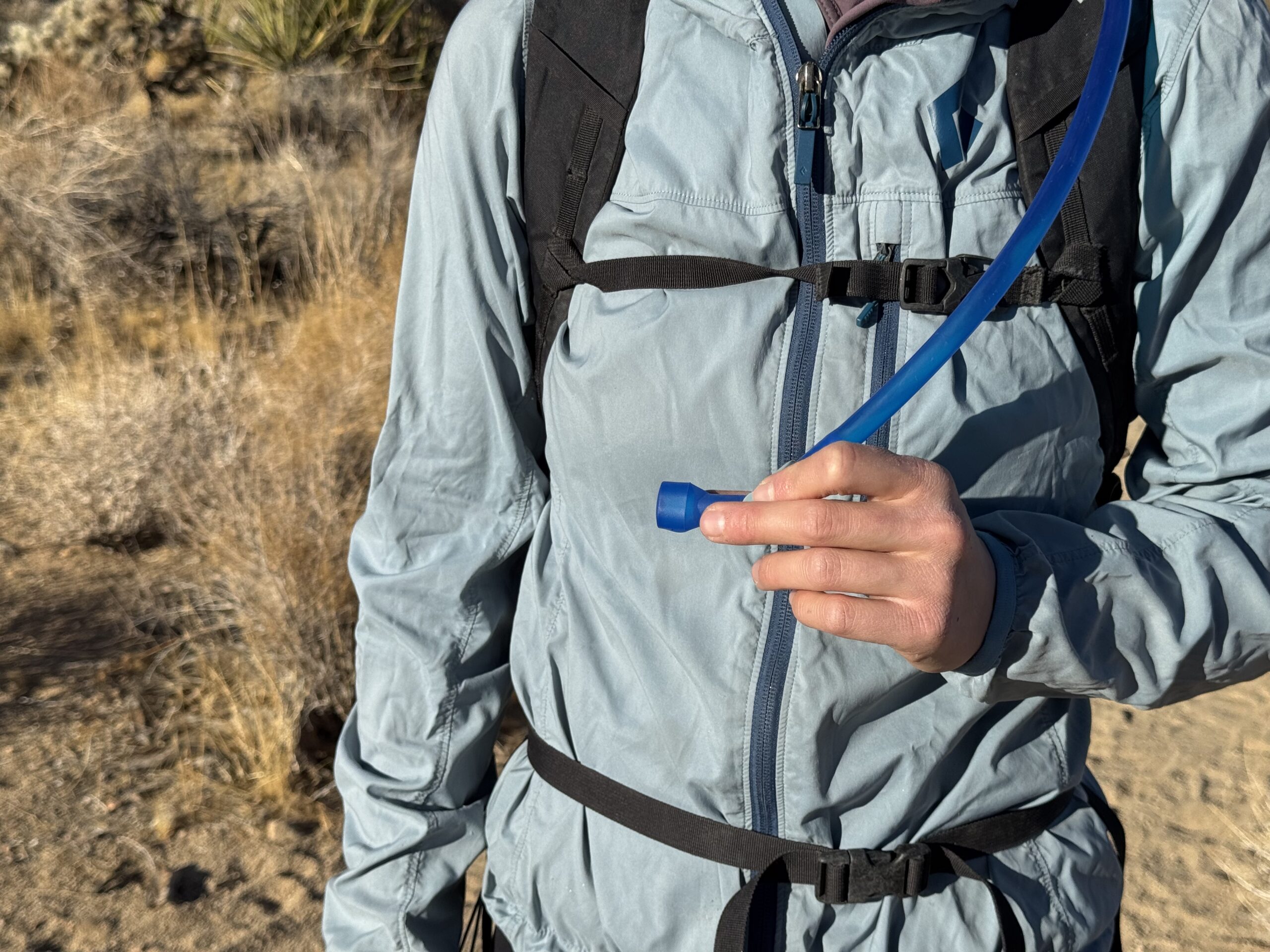 Close up photo of hiker holding the CamelBak Crux's hydration hose.