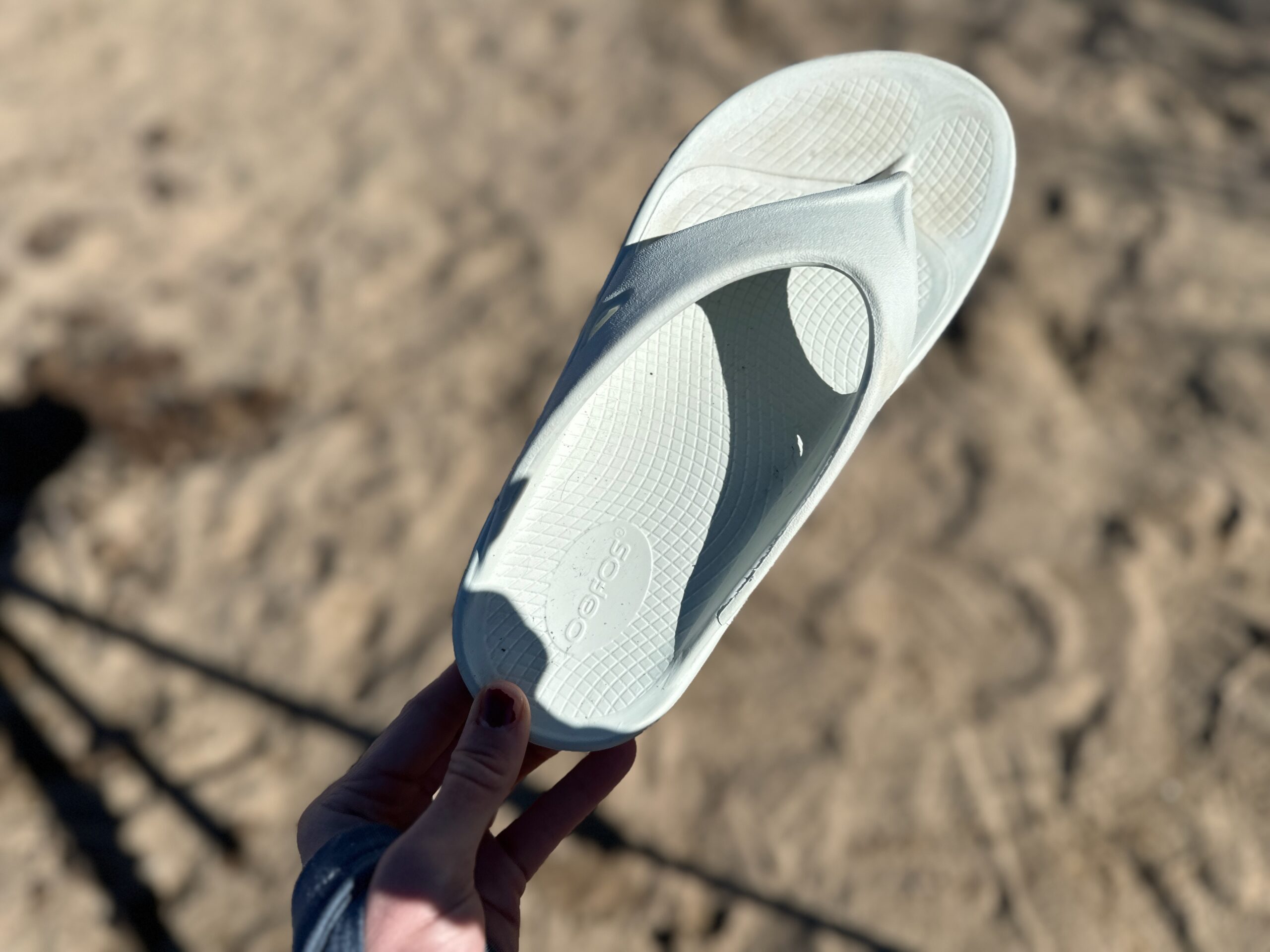 the OOfos OOriginals held up to show off the foam material of the shoe