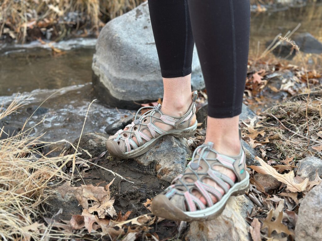 a woman wears the Keen Whisper by a creek