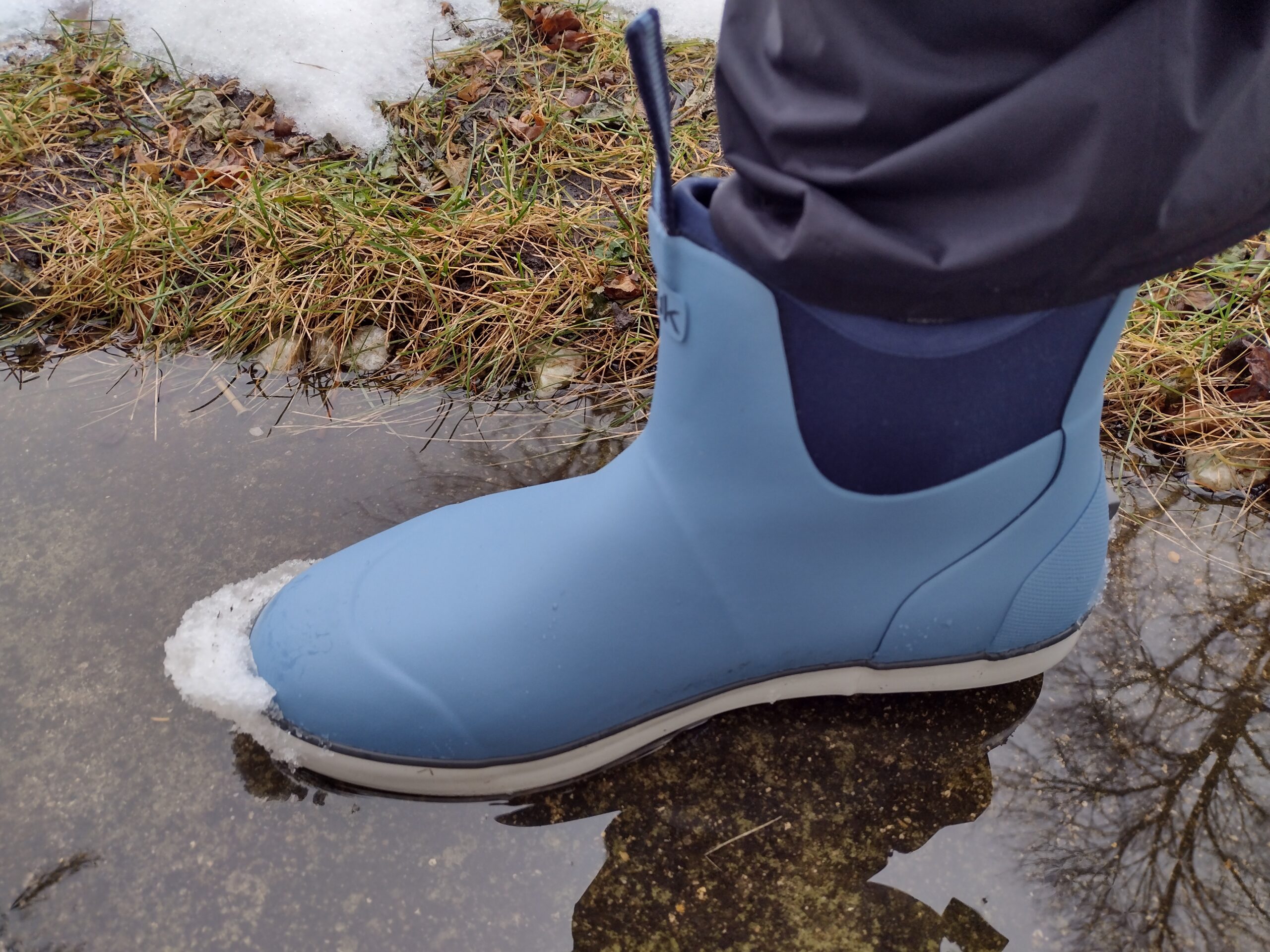 A ground level view of someone wearing the light blue Huk Rogue Wave boot.