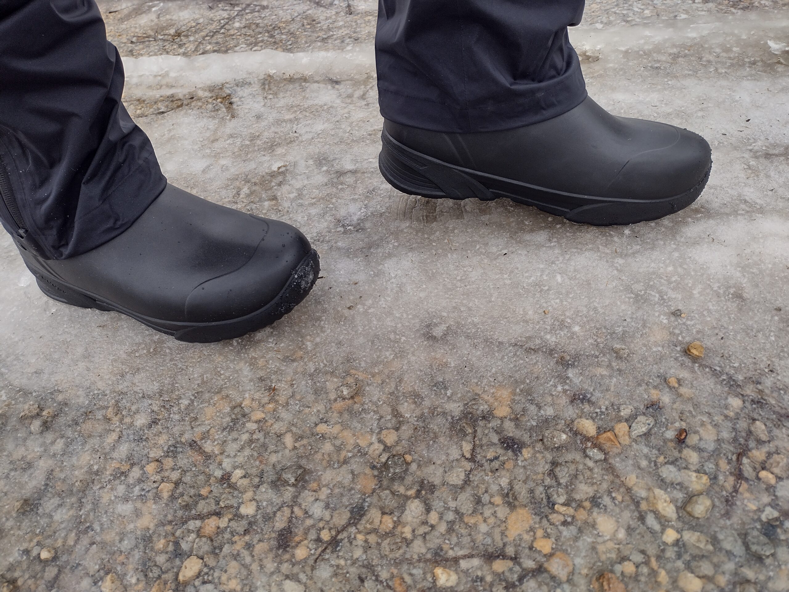 Ground level view of someone wearing the black Bozeman Mid boots on ice.