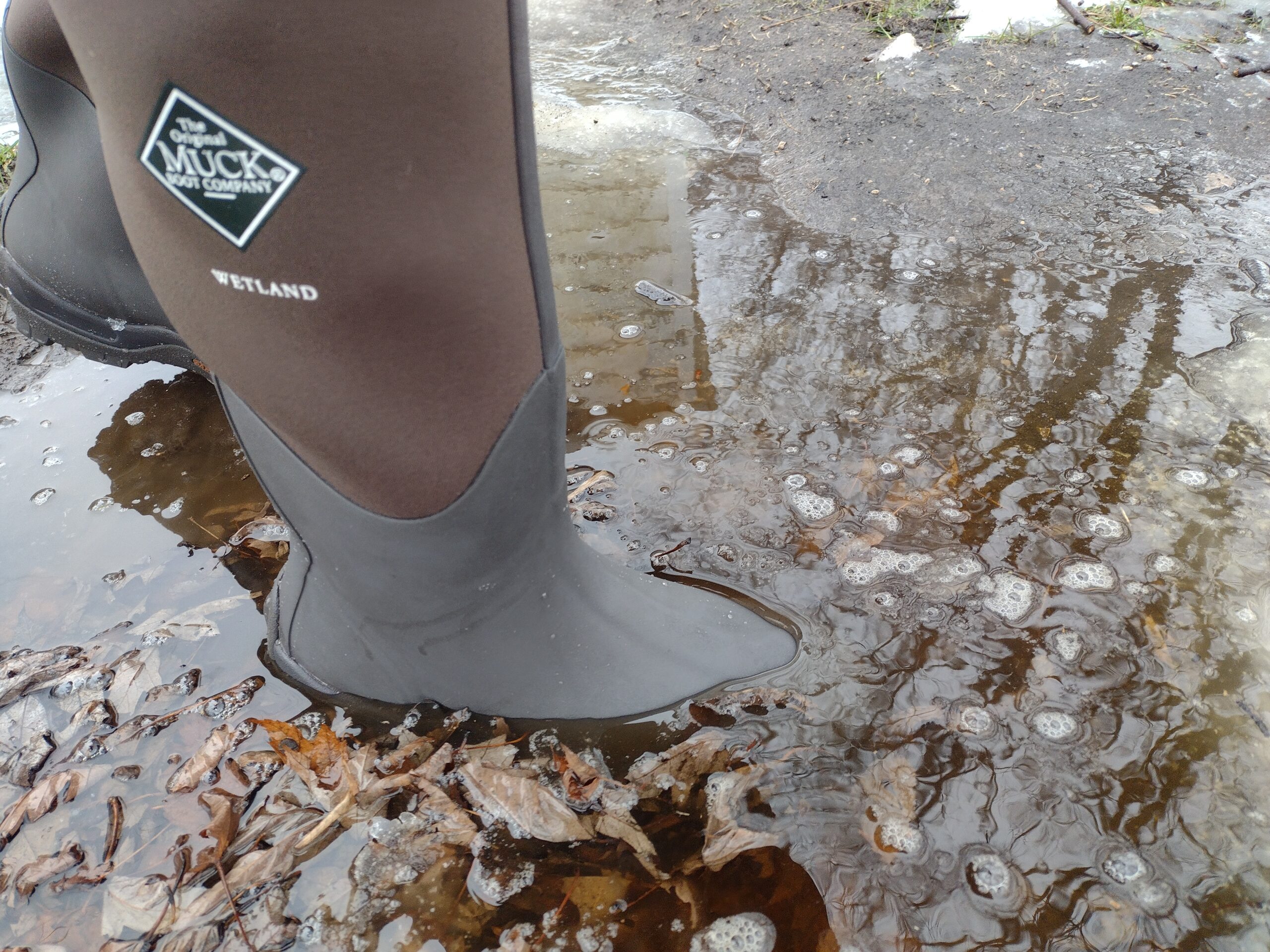 Ground level view of someone wearing the brown Original Muck Boot Wetland standing in deep water.