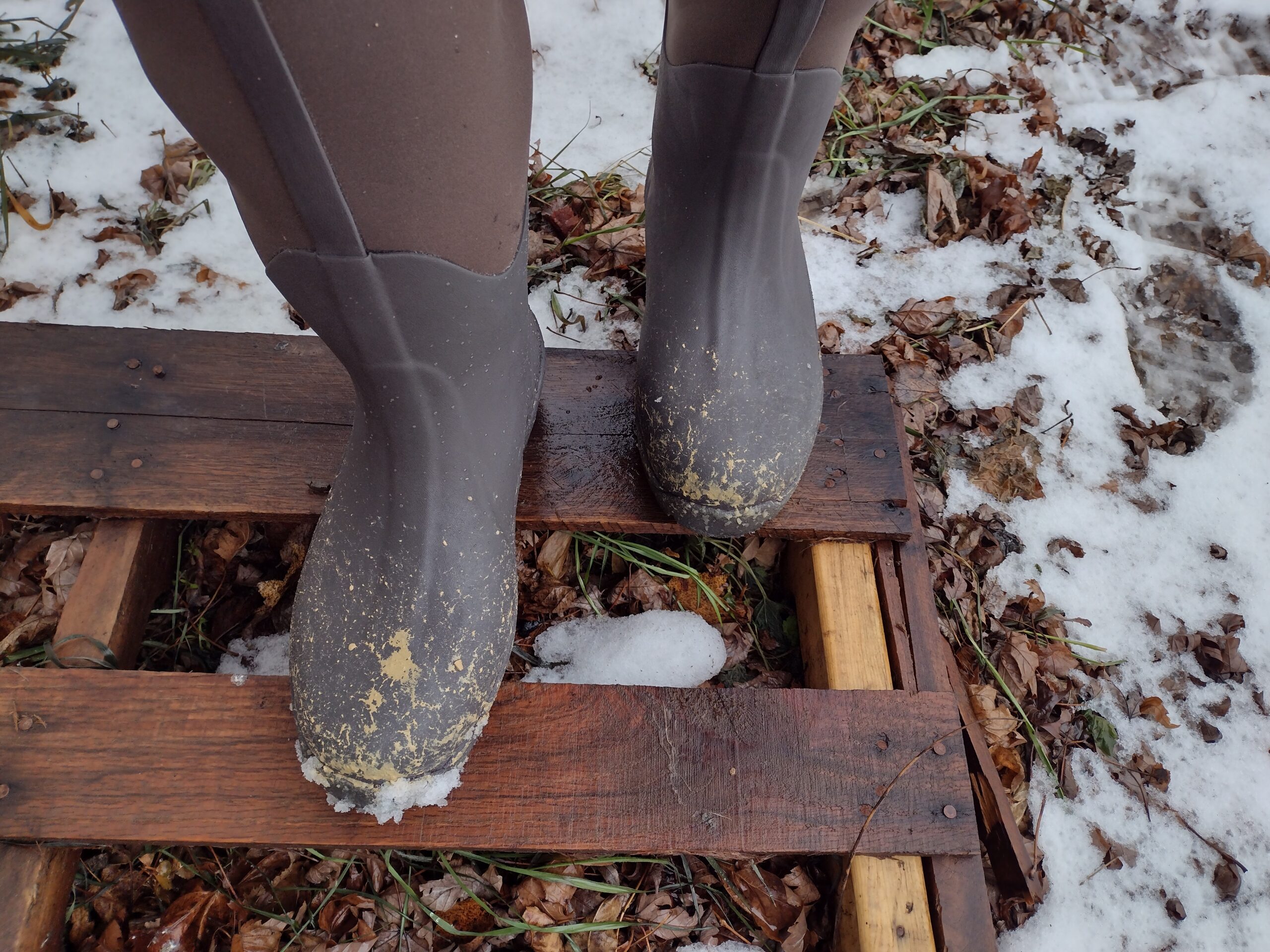 Ground level view of someone wearing the brown Original Muck Boot Wetland standing on a pallet.
