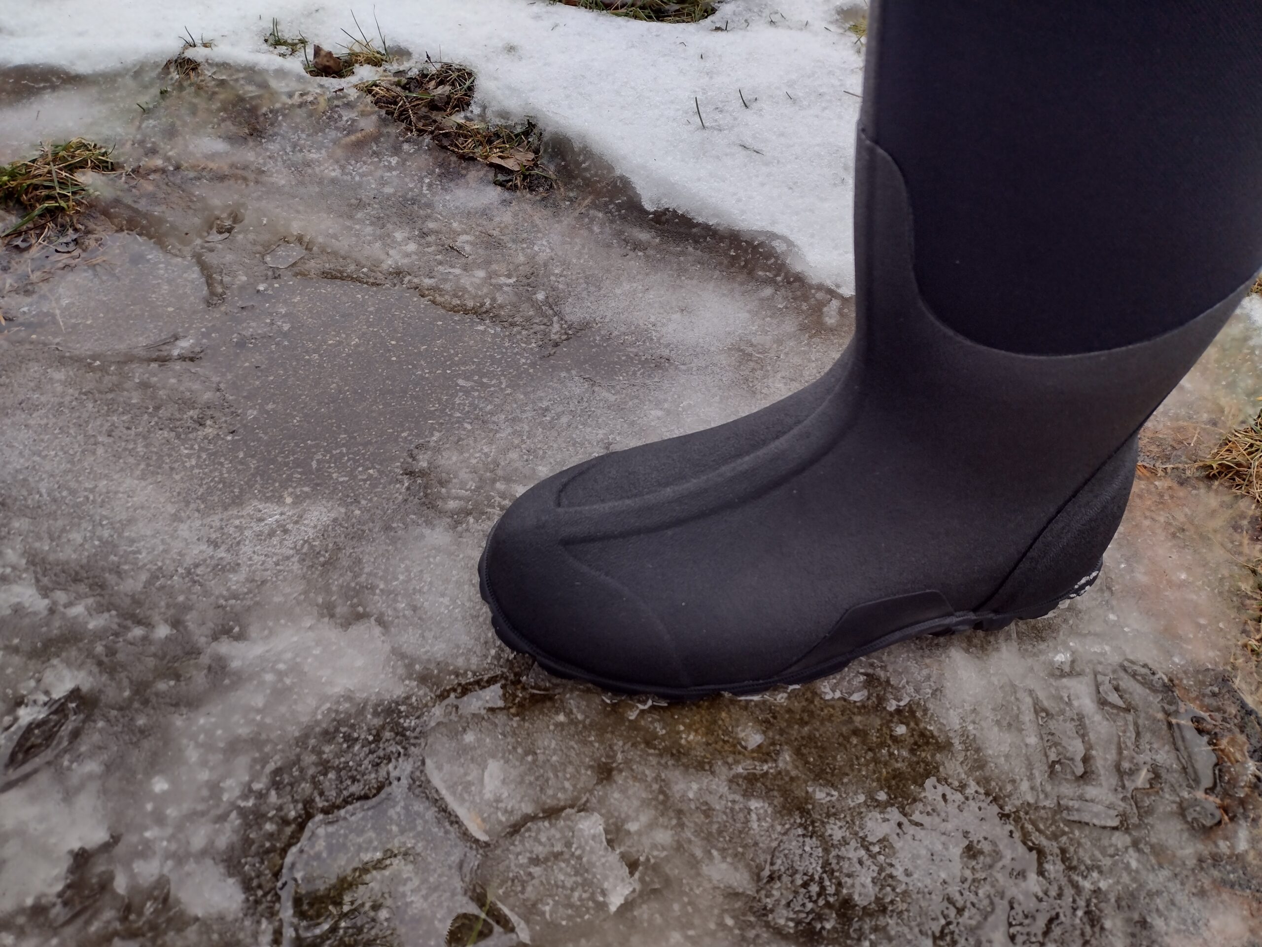 Ground level view of someone wearing the black Bogs Classic High standing on ice.