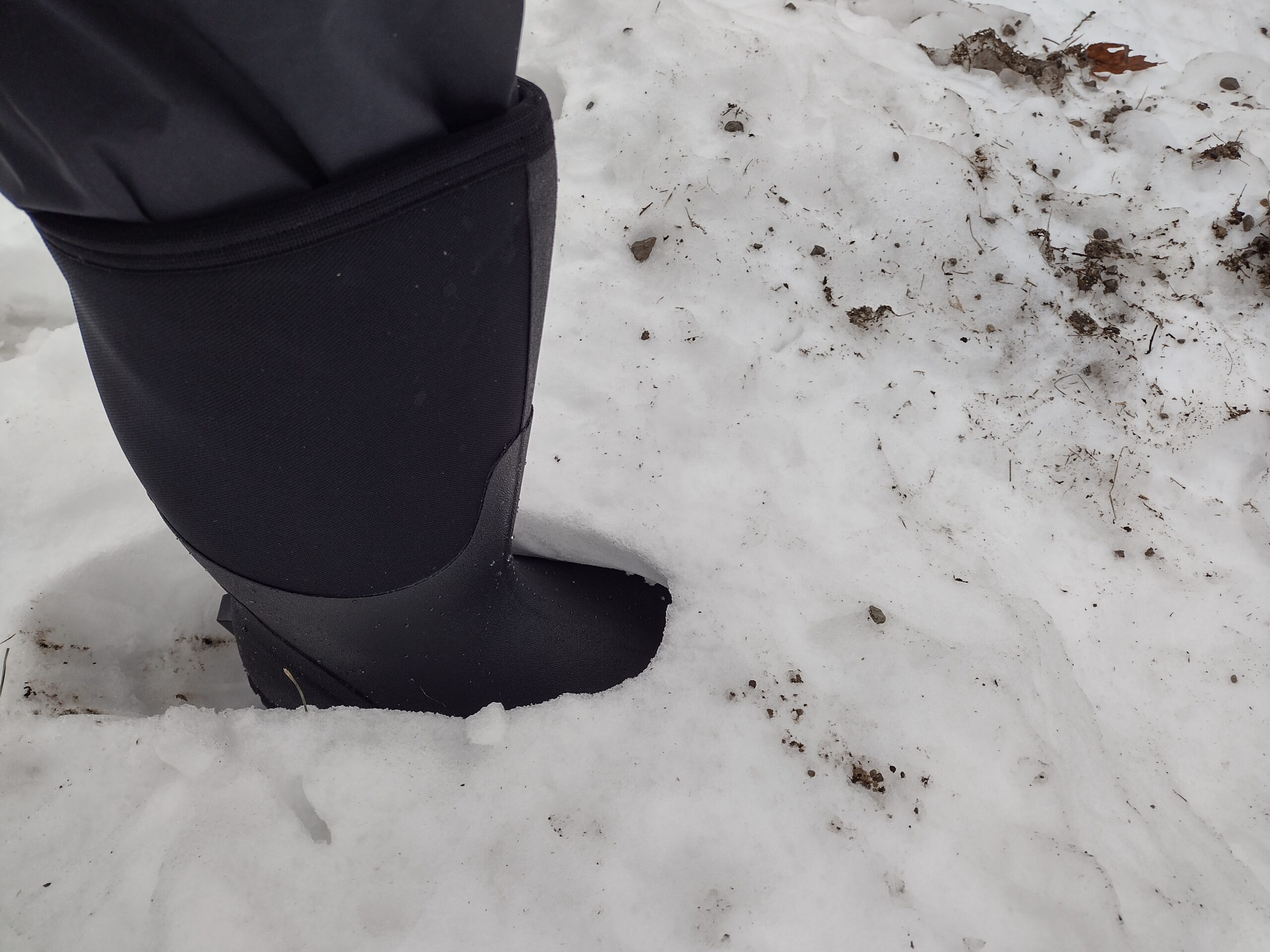 Ground level view of someone wearing the black Bogs Classic High standing in deep snow.
