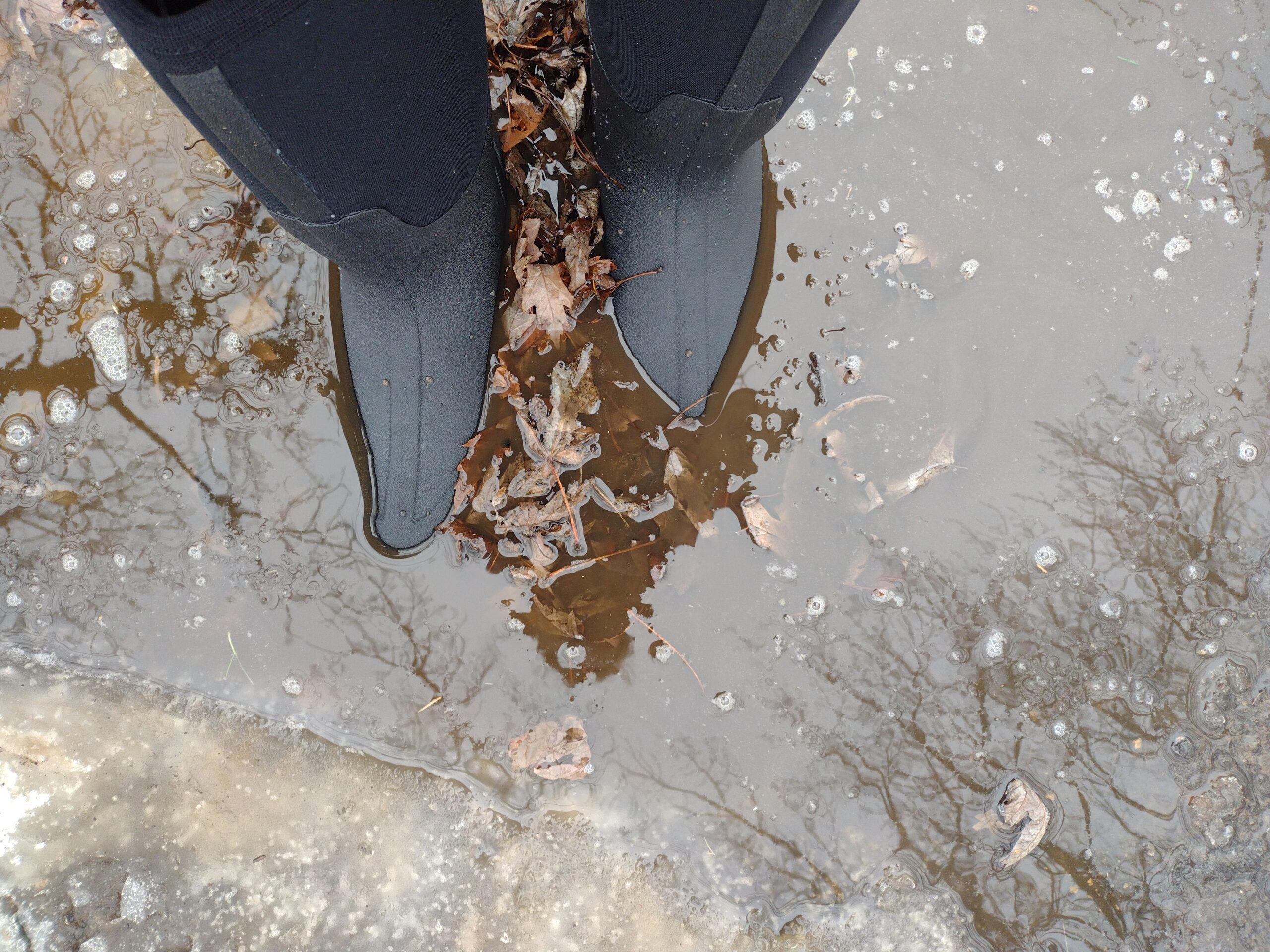 Ground level view of someone wearing the black Bogs Classic High standing in deep water.