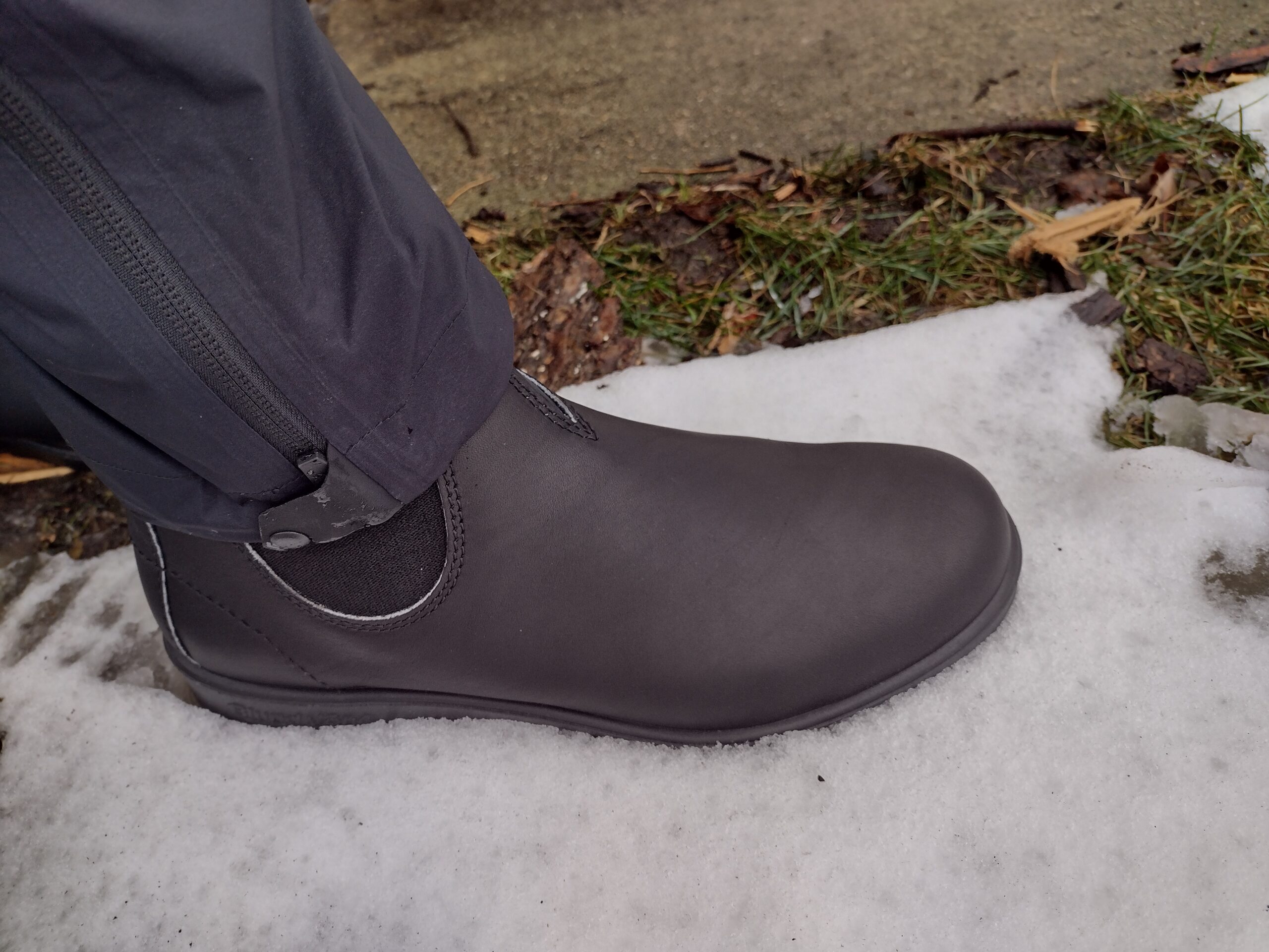 Ground level view of someone wearing the black Blundstone Original Chelsea standing in light snow.