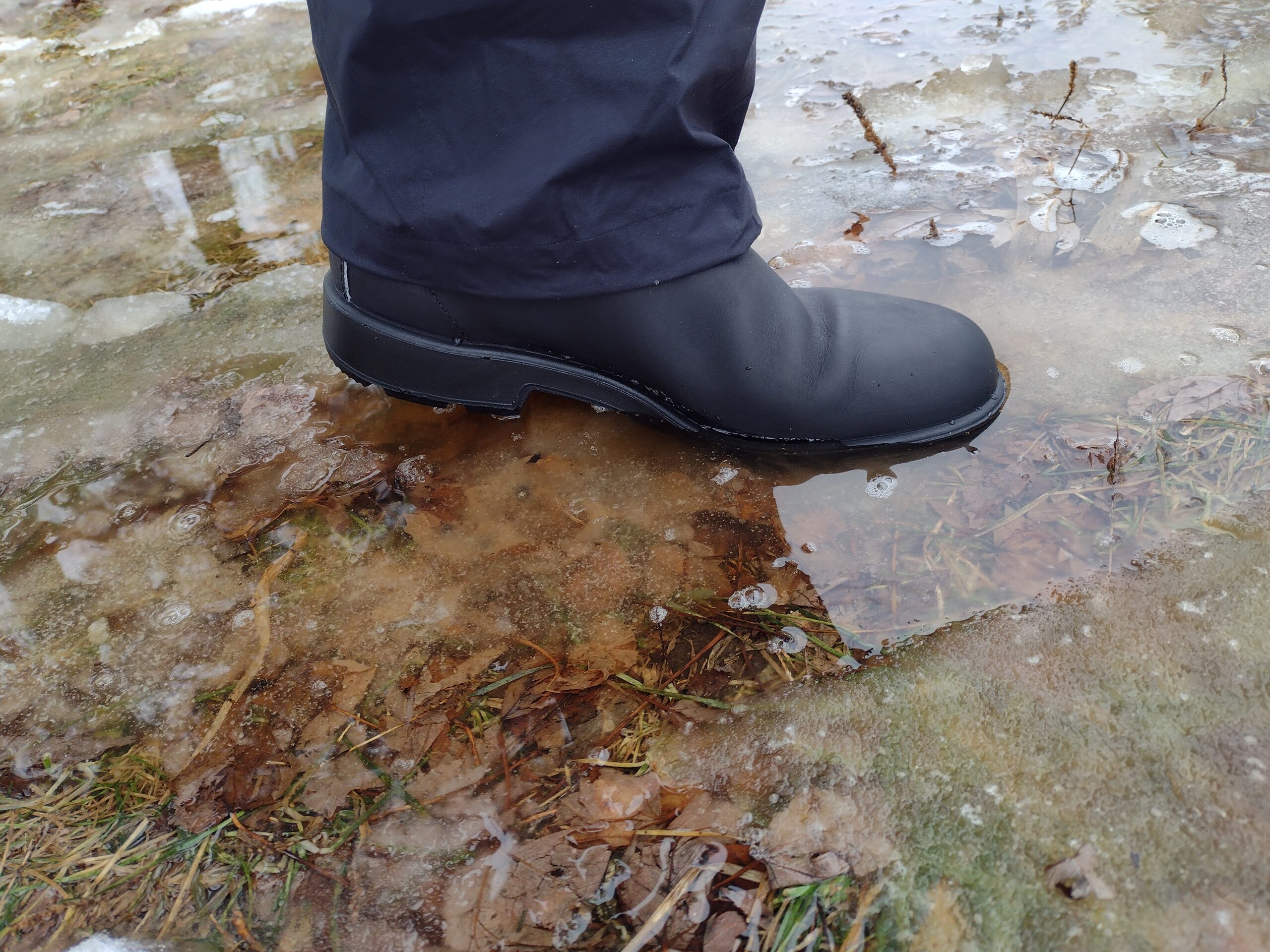 Ground level view of someone wearing the black Blundstone Original Chelsea standing in a puddle.