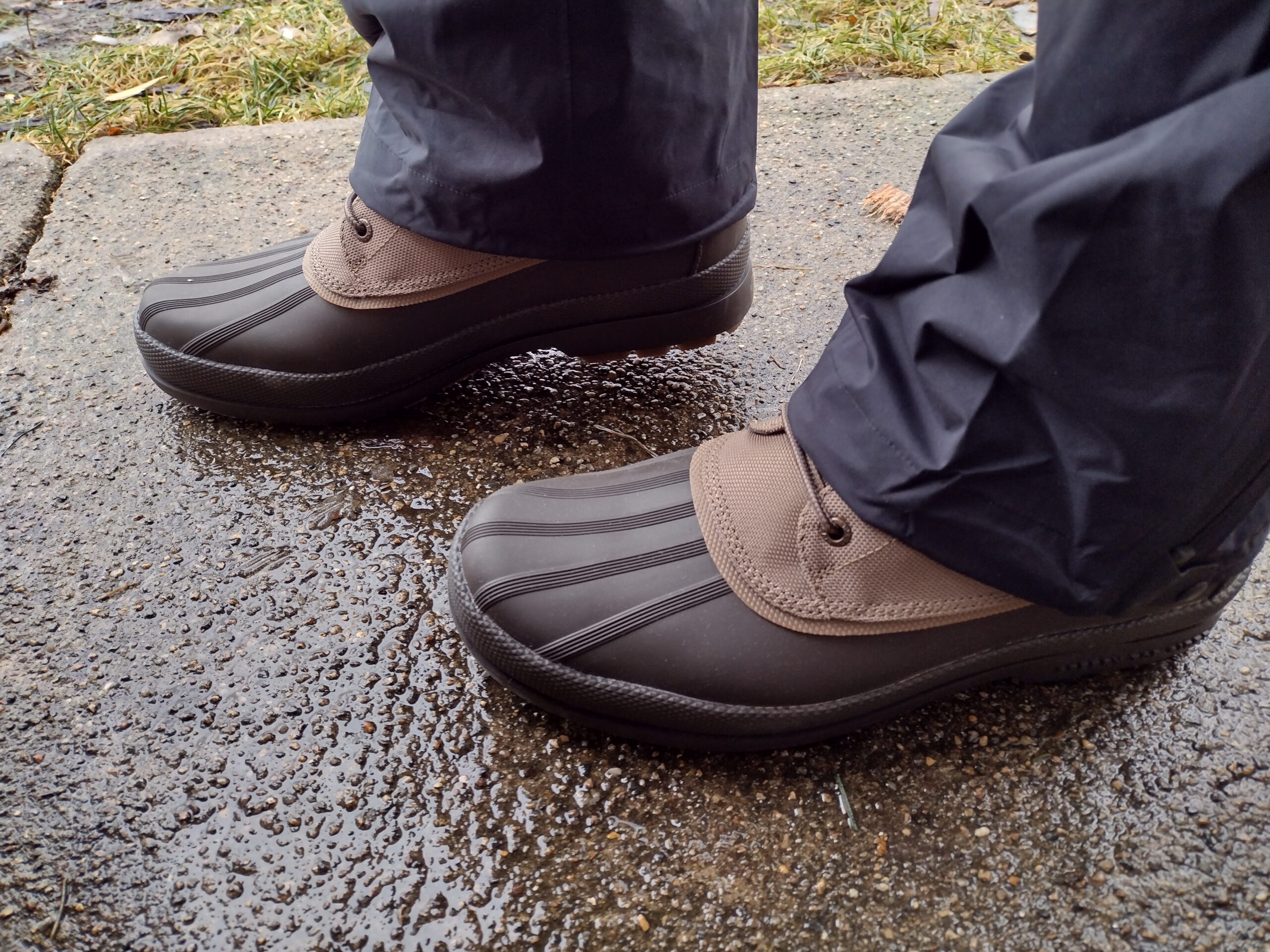 Ground level view of someone wearing the brown Sperry Cold Bay Chukka on a wet sidewalk.