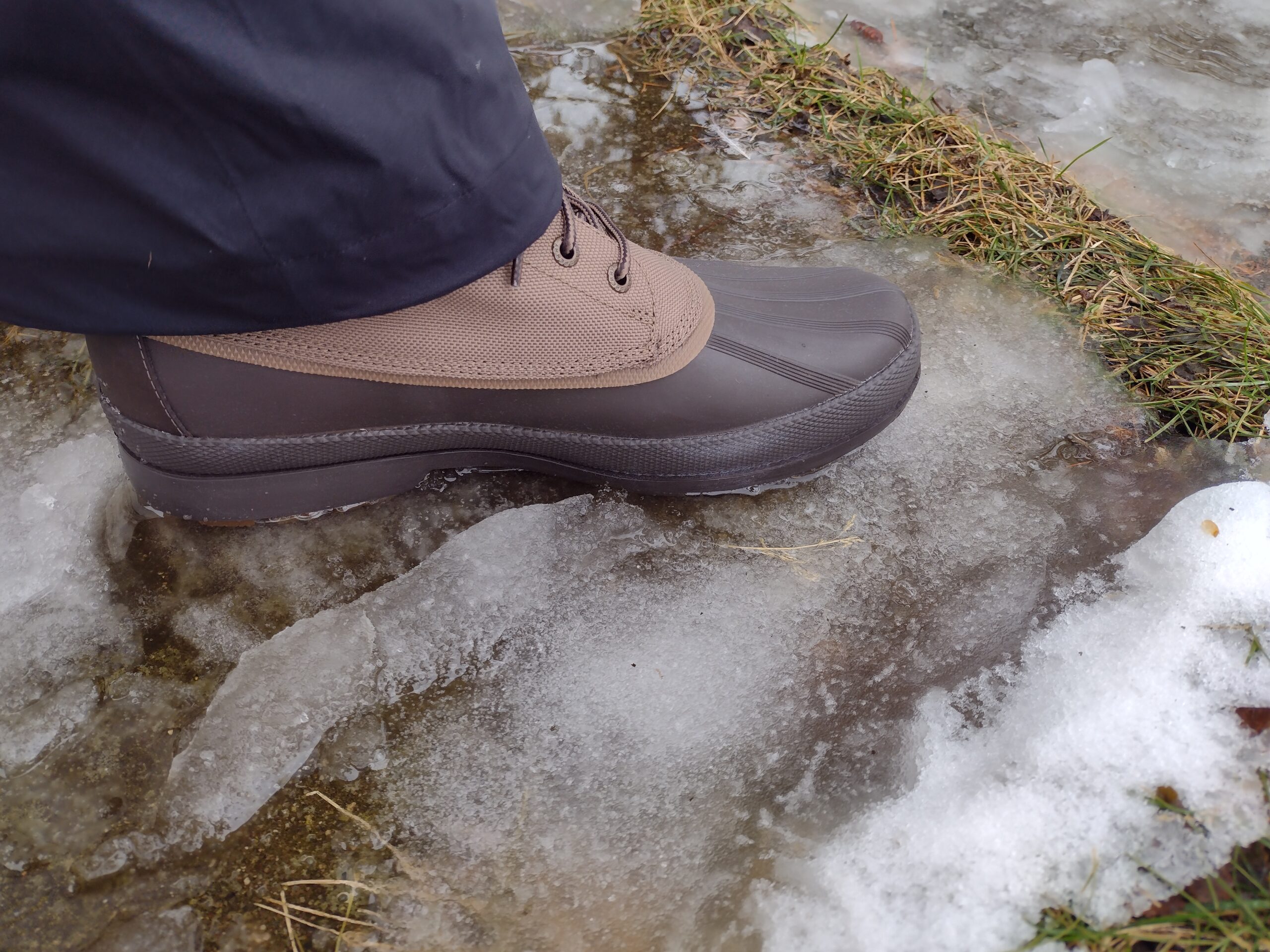 Ground level view of someone wearing the brown Sperry Cold Bay Chukka on icy ground.