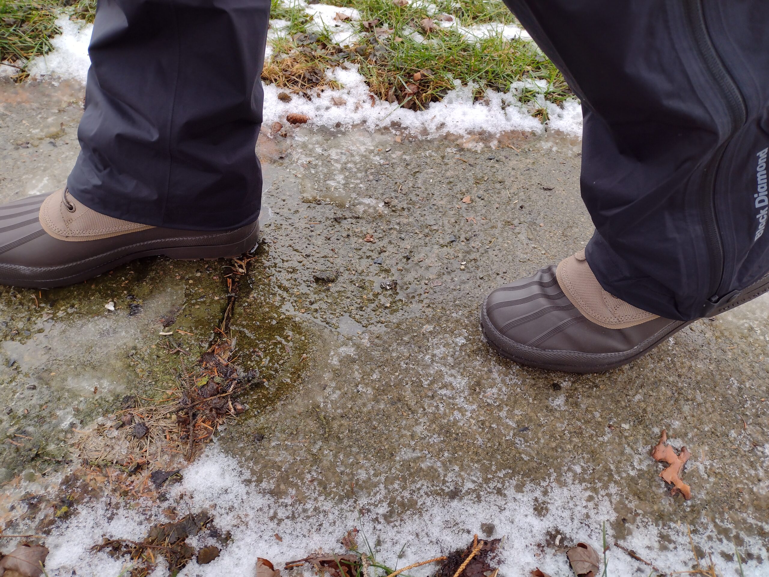 Ground level view of someone wearing the brown Sperry Cold Bay Chukka on a wet sidewalk.
