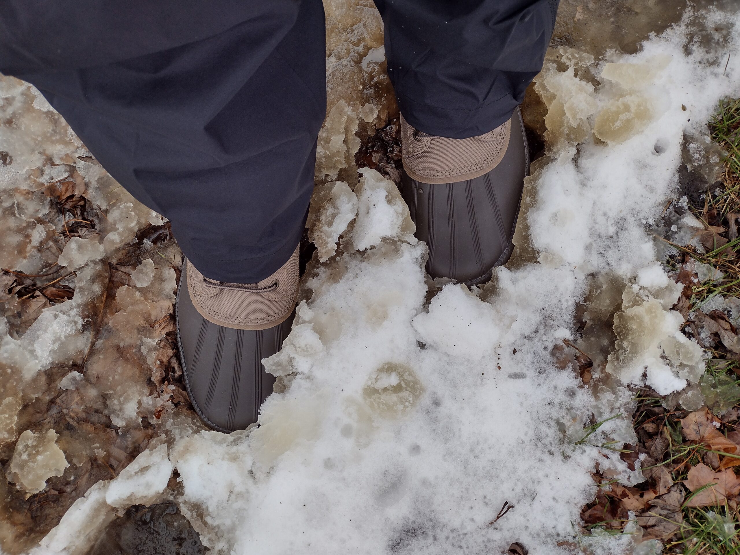 Ground level view of someone wearing the brown Sperry Cold Bay Chukka in slushy snow.