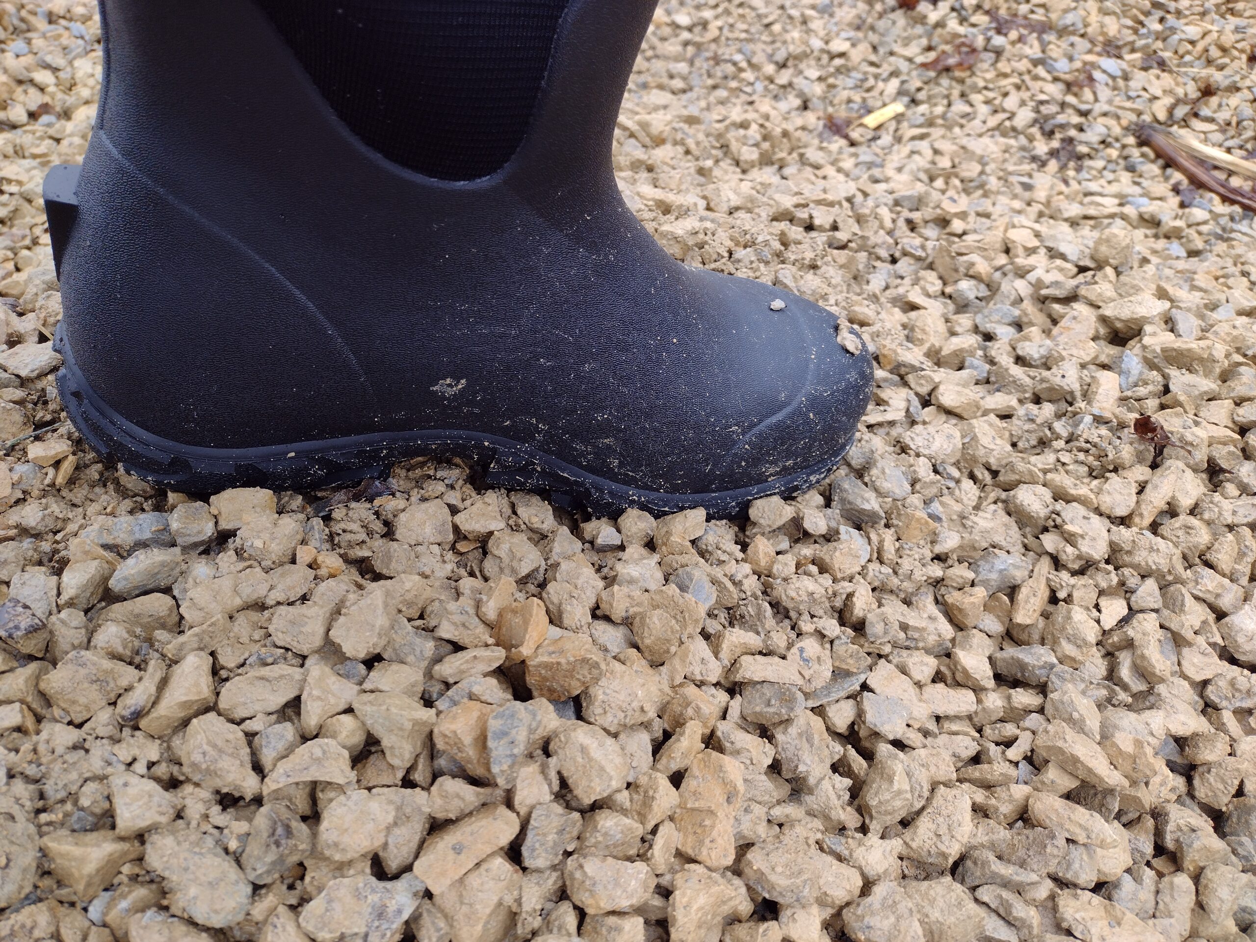 Ground level view of someone wearing the black Bogs Workman in muddy snow and water.