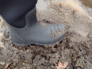 Ground level view of someone wearing the black Bogs Workman in muddy snow and water.