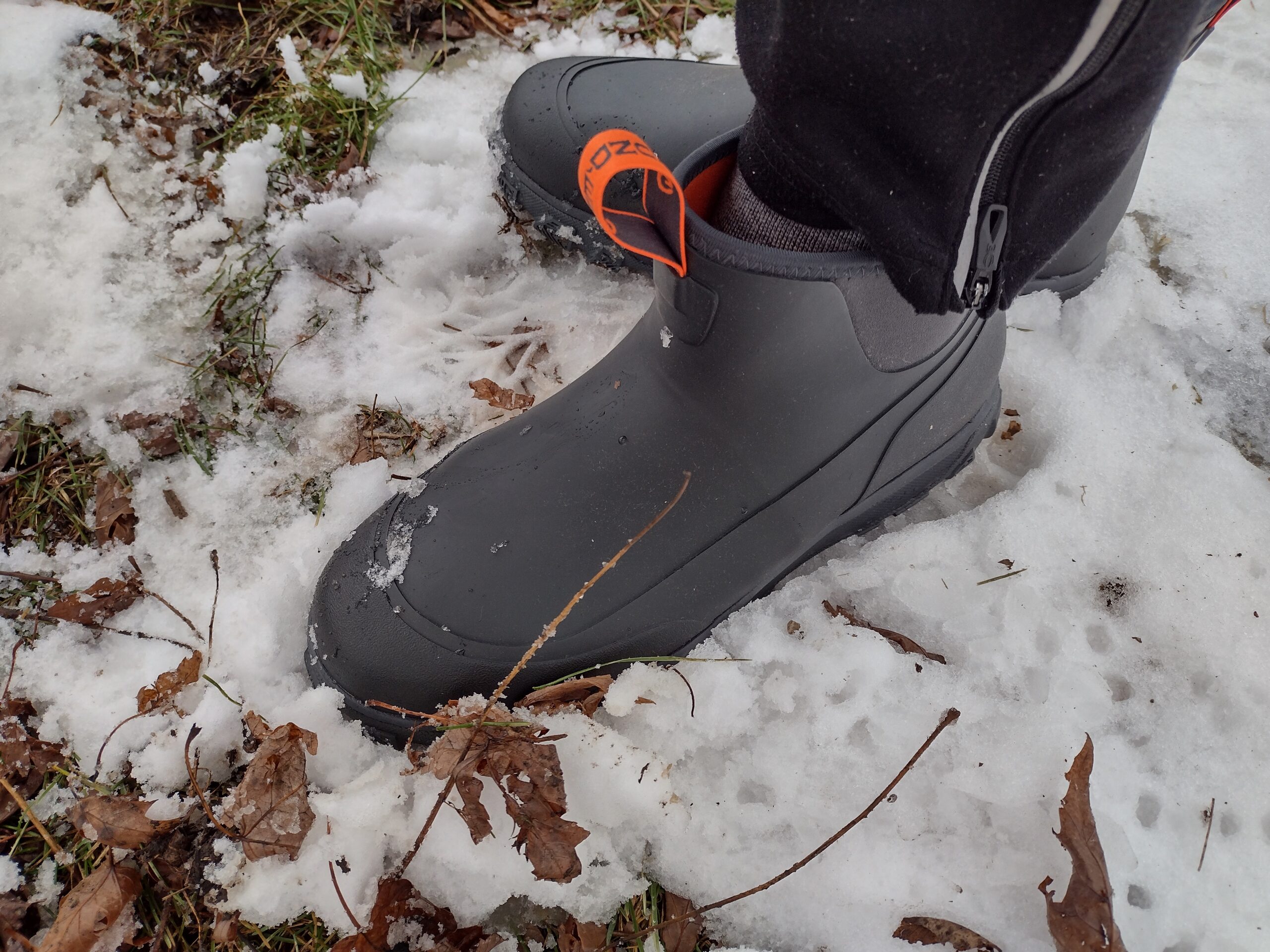 Ground level view of someone wearing the black Grundens Deviation Ankle Boot on snow.