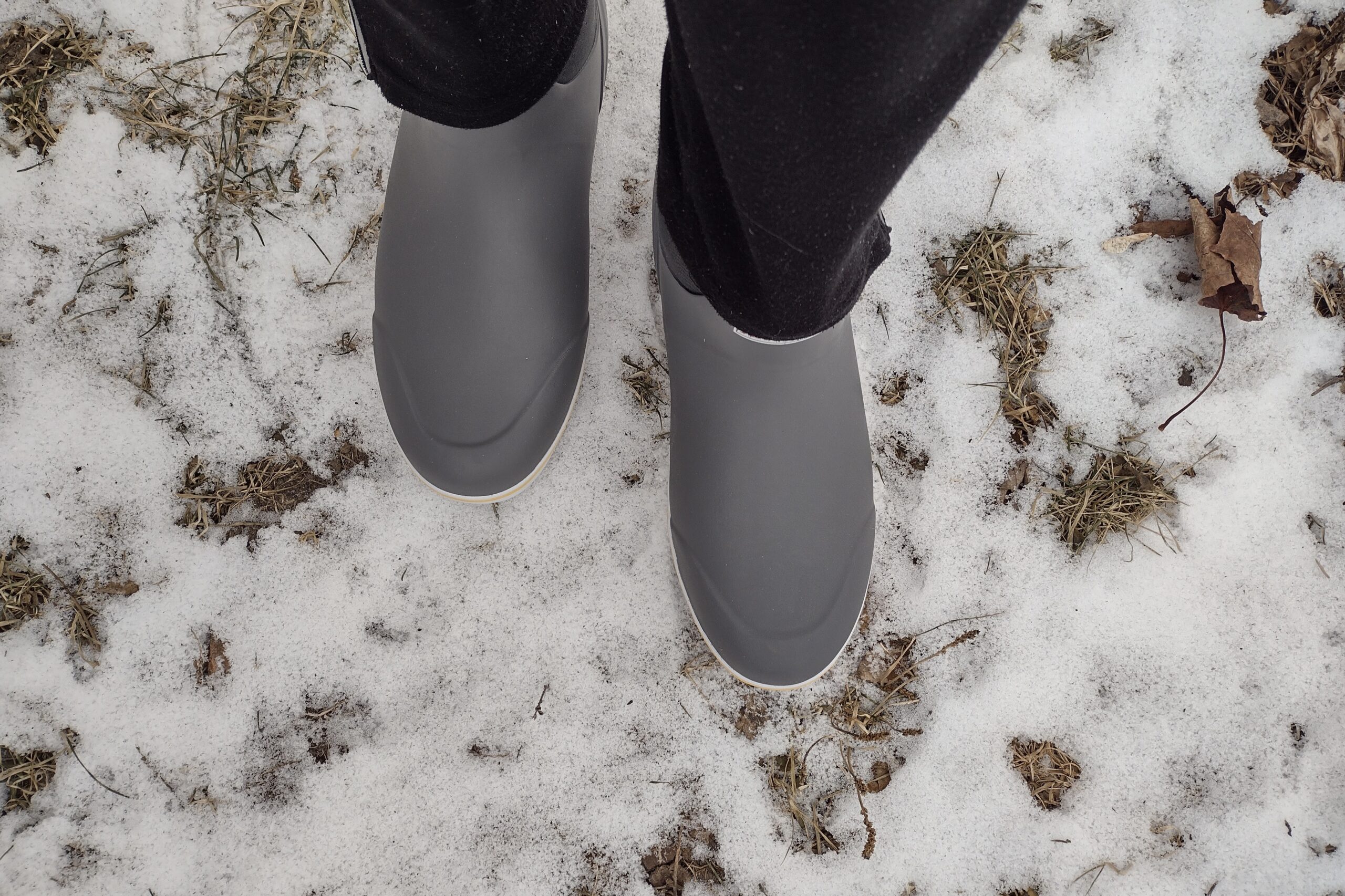 Ground level view of someone wearing the gray XTRATUF Ankle Deck Boot in light snow.