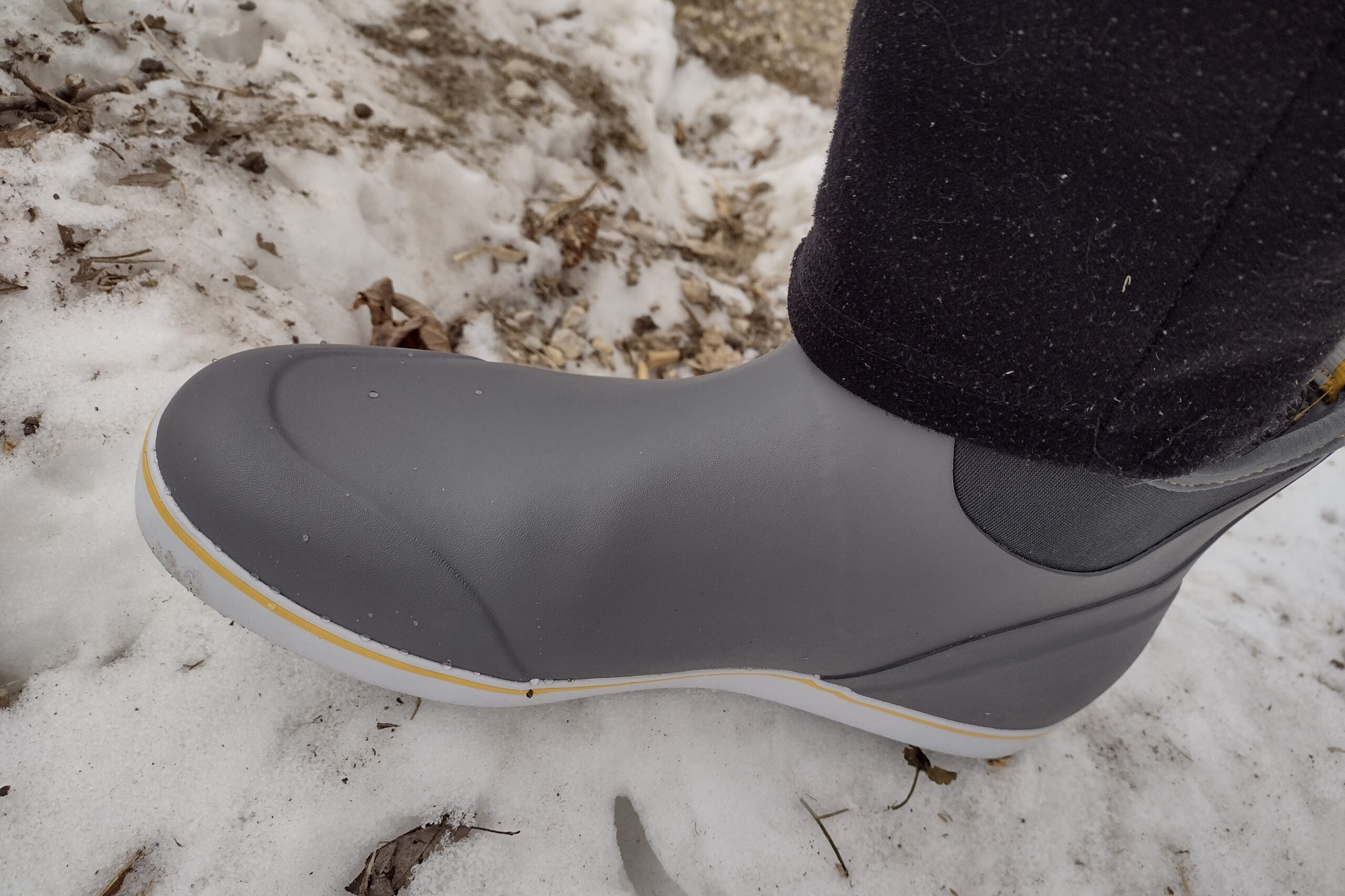 Ground level view of someone wearing the gray XTRATUF Ankle Deck Boot on snow.