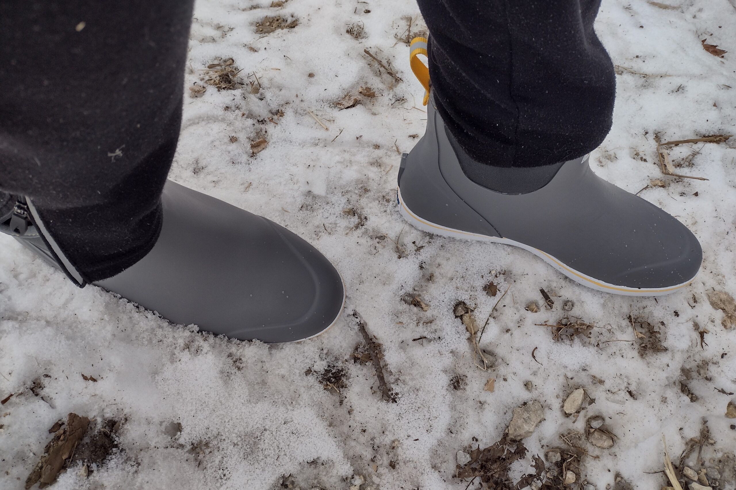 Ground level view of someone wearing the gray XTRATUF Ankle Deck Boot on snow.