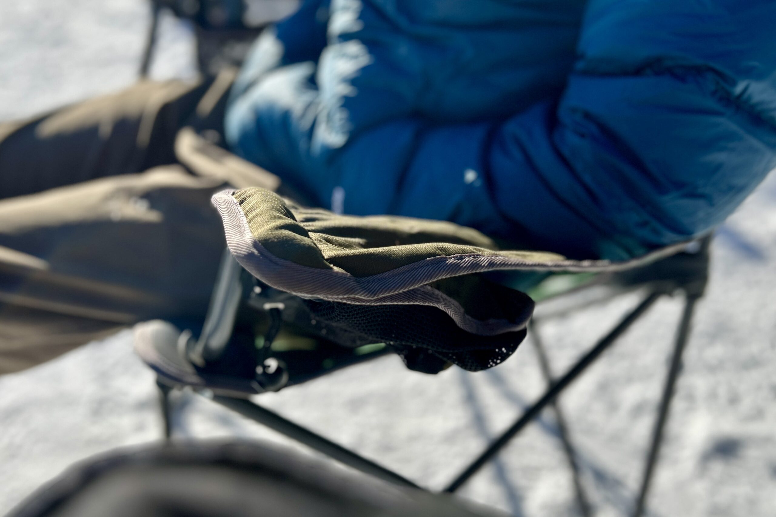 Close up of a person's elbow resting on an armrest of a camping chair.