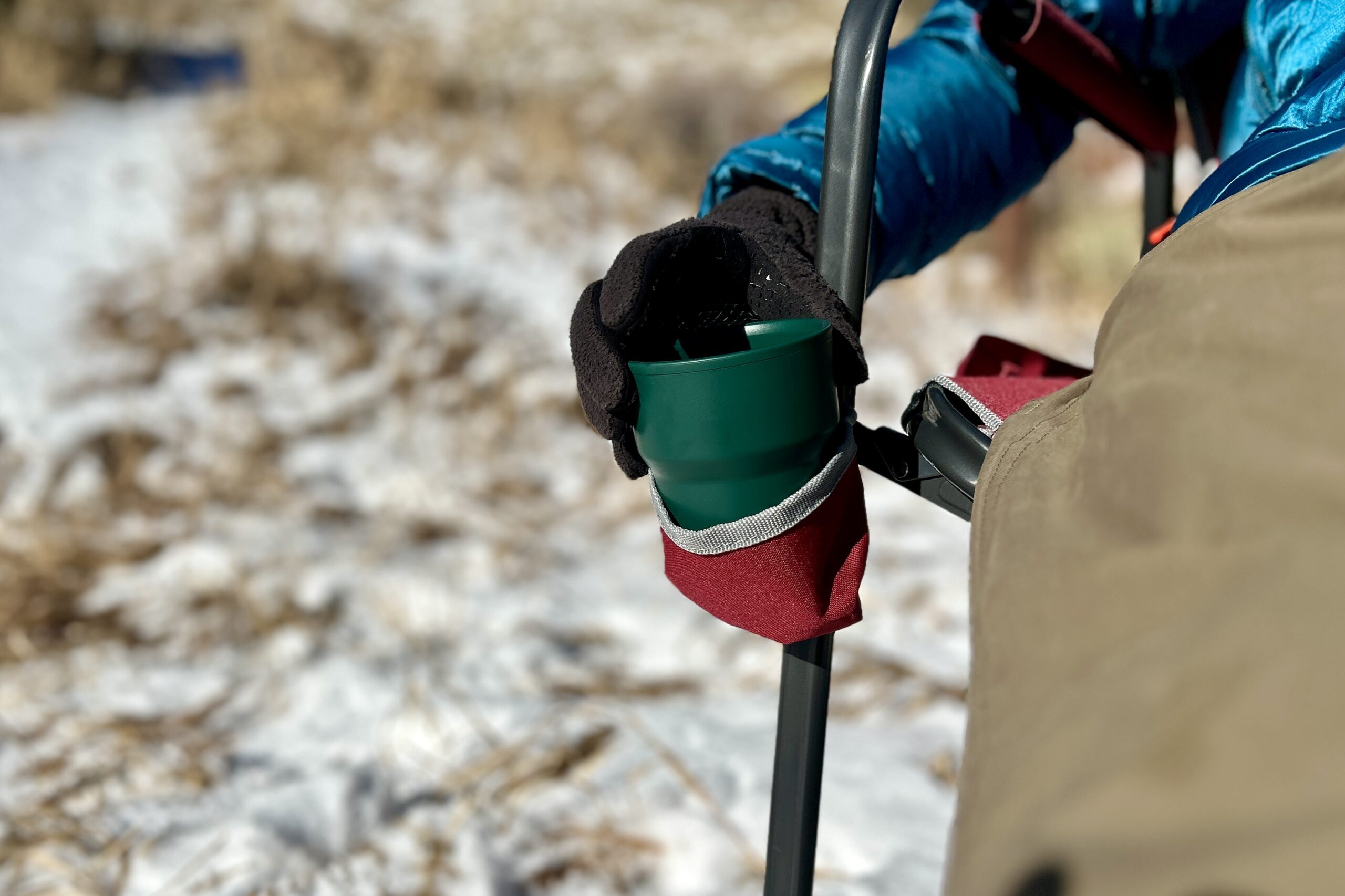 Close up of a person placing a mug in a fabric cupholder of a camping chair.
