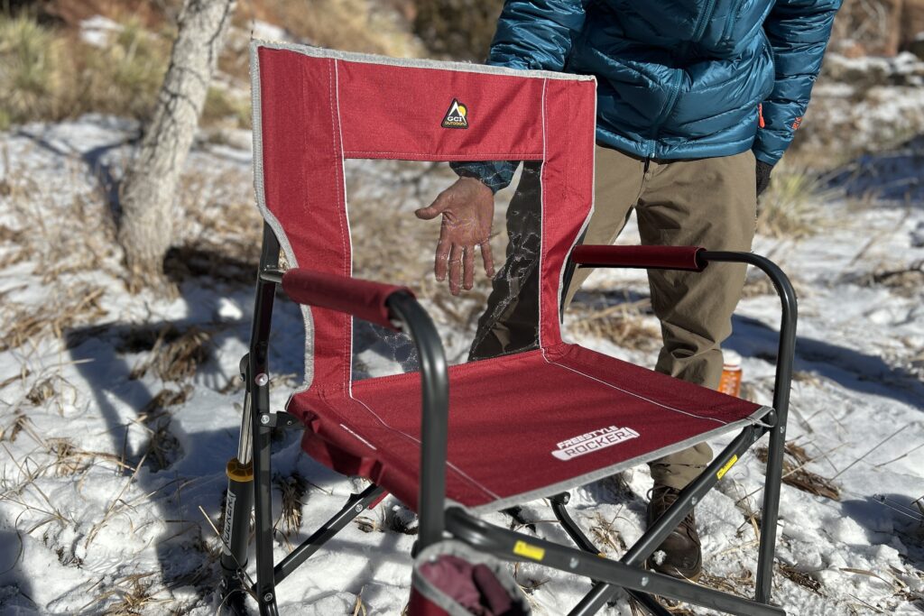 A person puts their hand behind the mesh back of a camping chair.