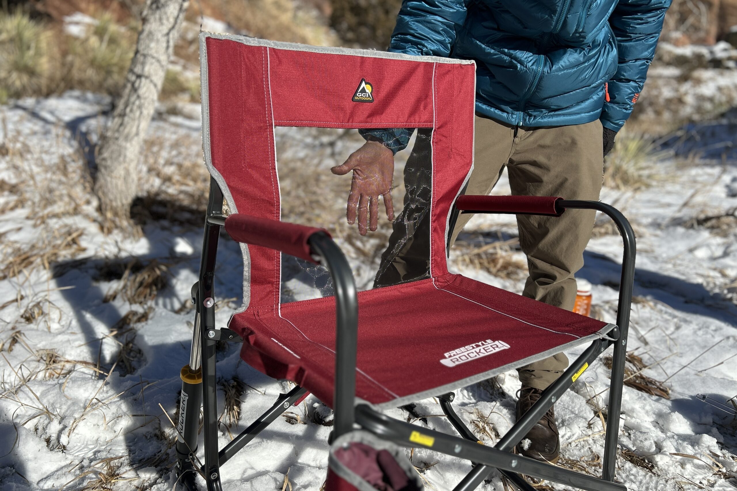 A person puts their hand behind the mesh back of a camping chair.