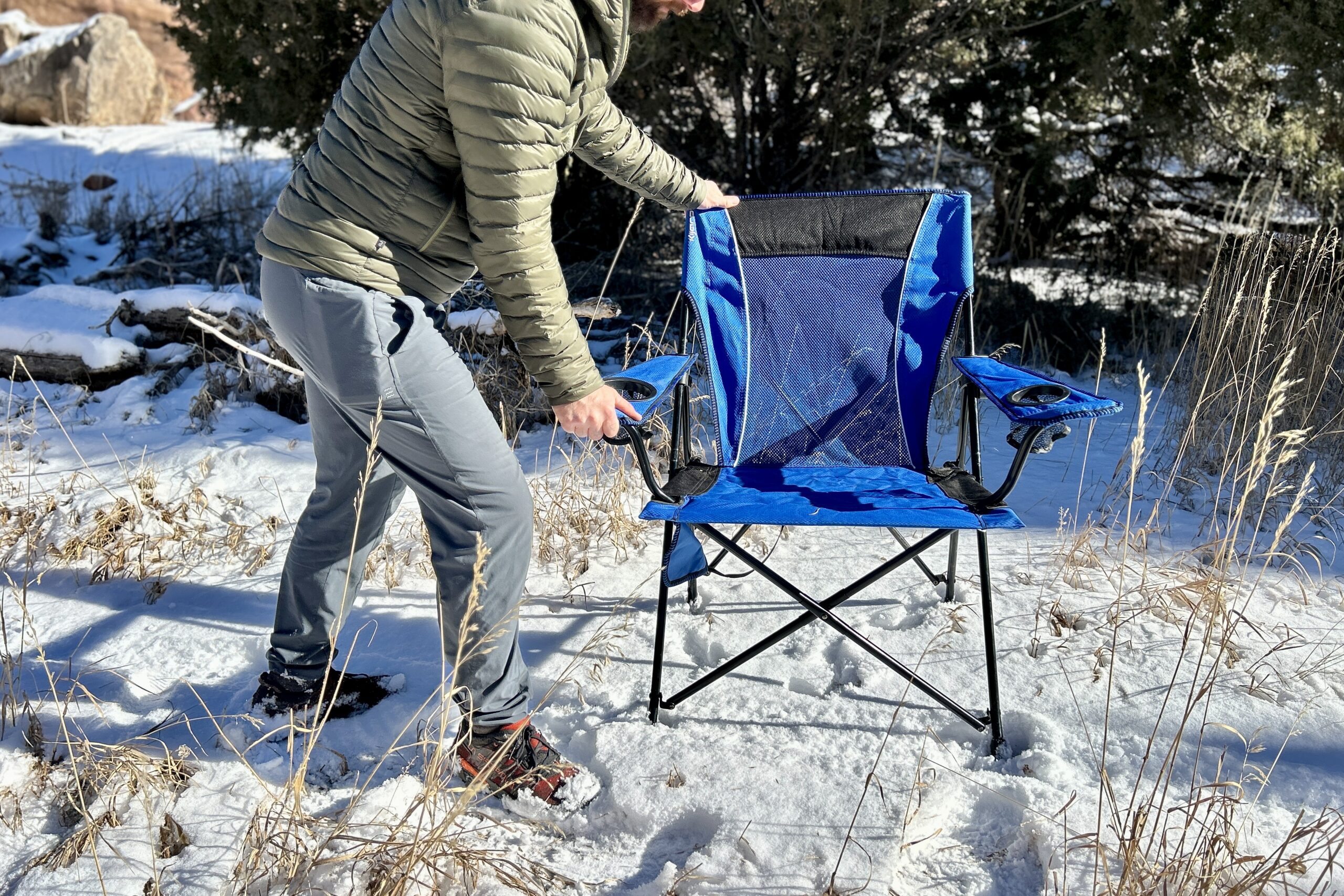 A person sets p a camping chair in a snowy landscape.