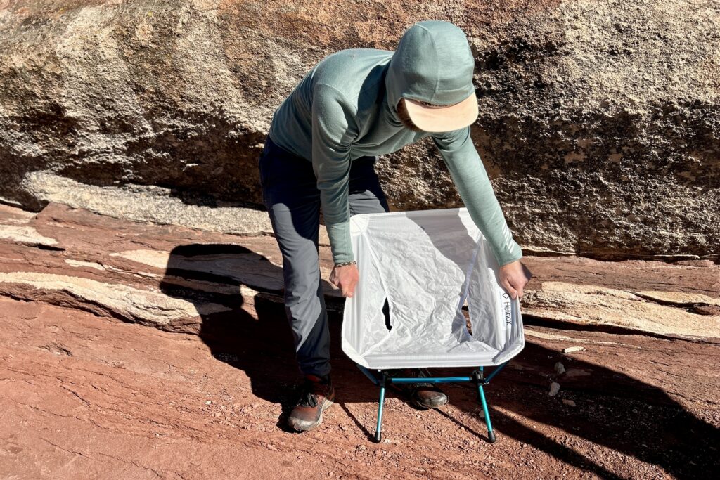 A person bends over while they move a camping chair.