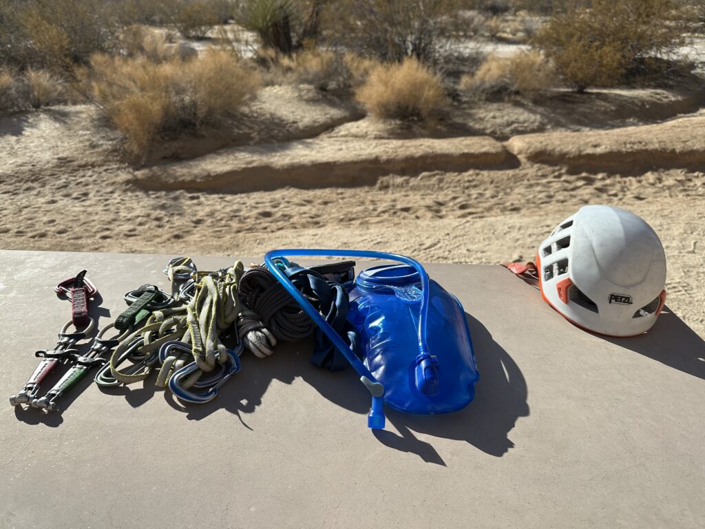 Photo of the CamelBak Crux bladder on a picnic table in the desert with some climbing gear and a climbing helmet.