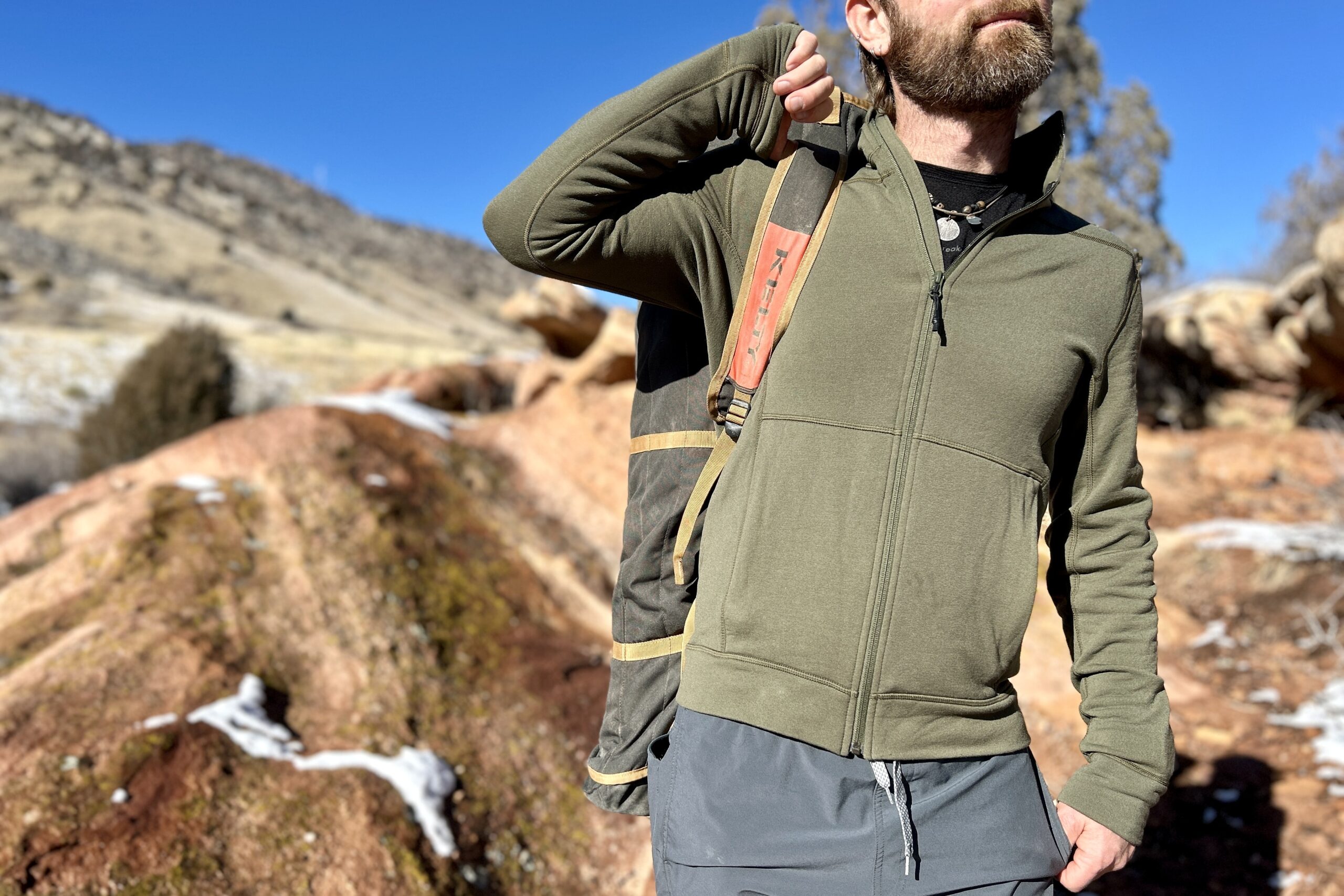A man uses the shoulder strap of a camping chair to carry it over his shoulder.
