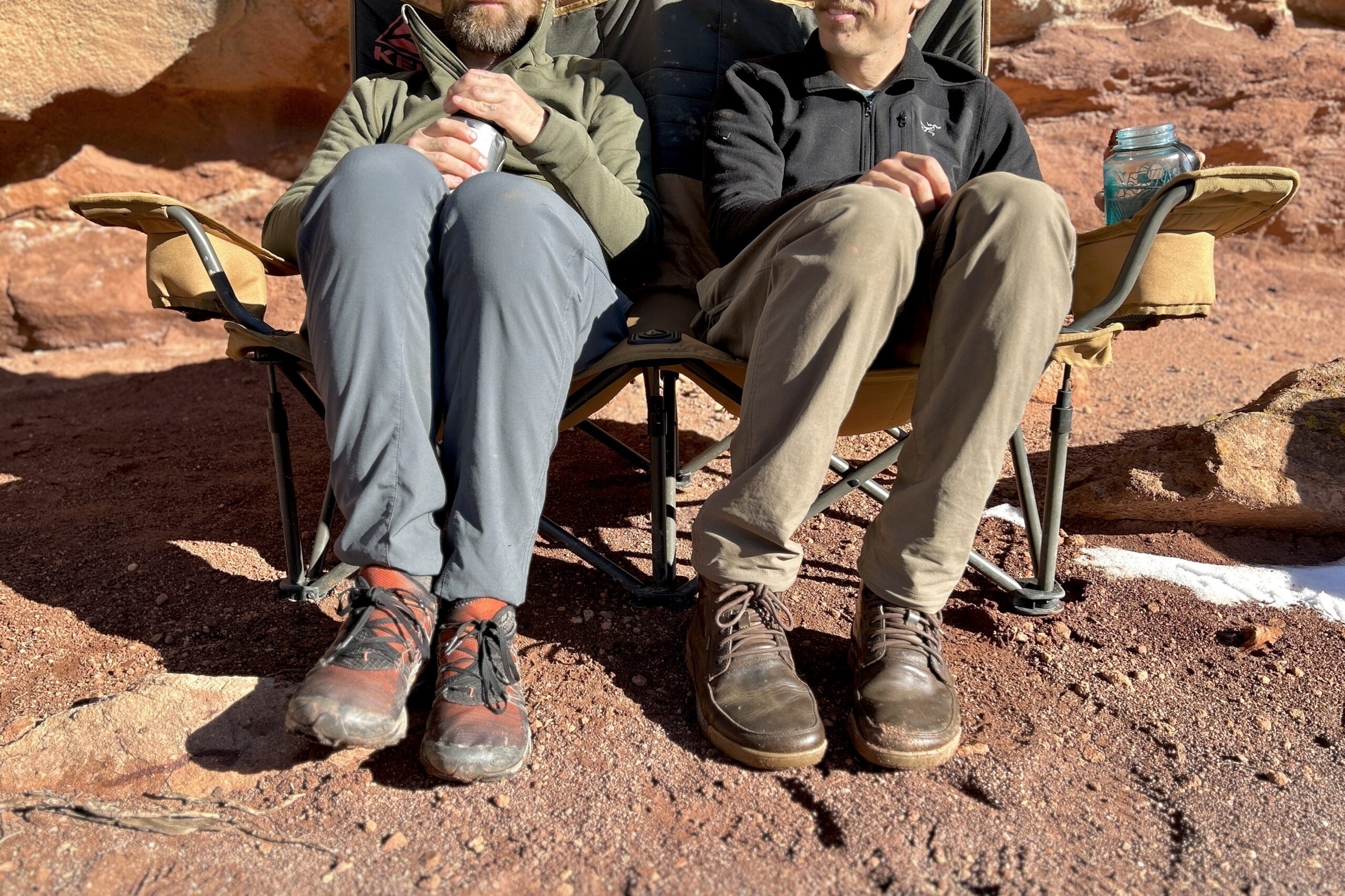 Close up of the bottom frame of a 2-person camping chair with 2 people sitting in it.