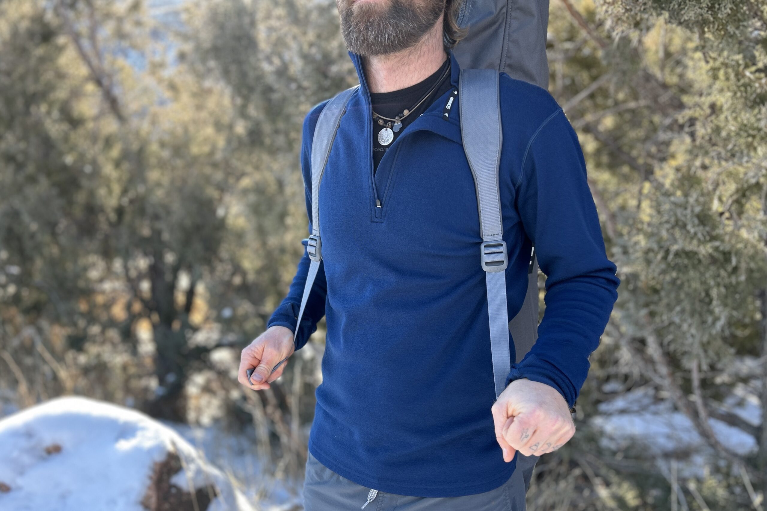 Close up of a man wearing a large camping chair in its case like a backpack.