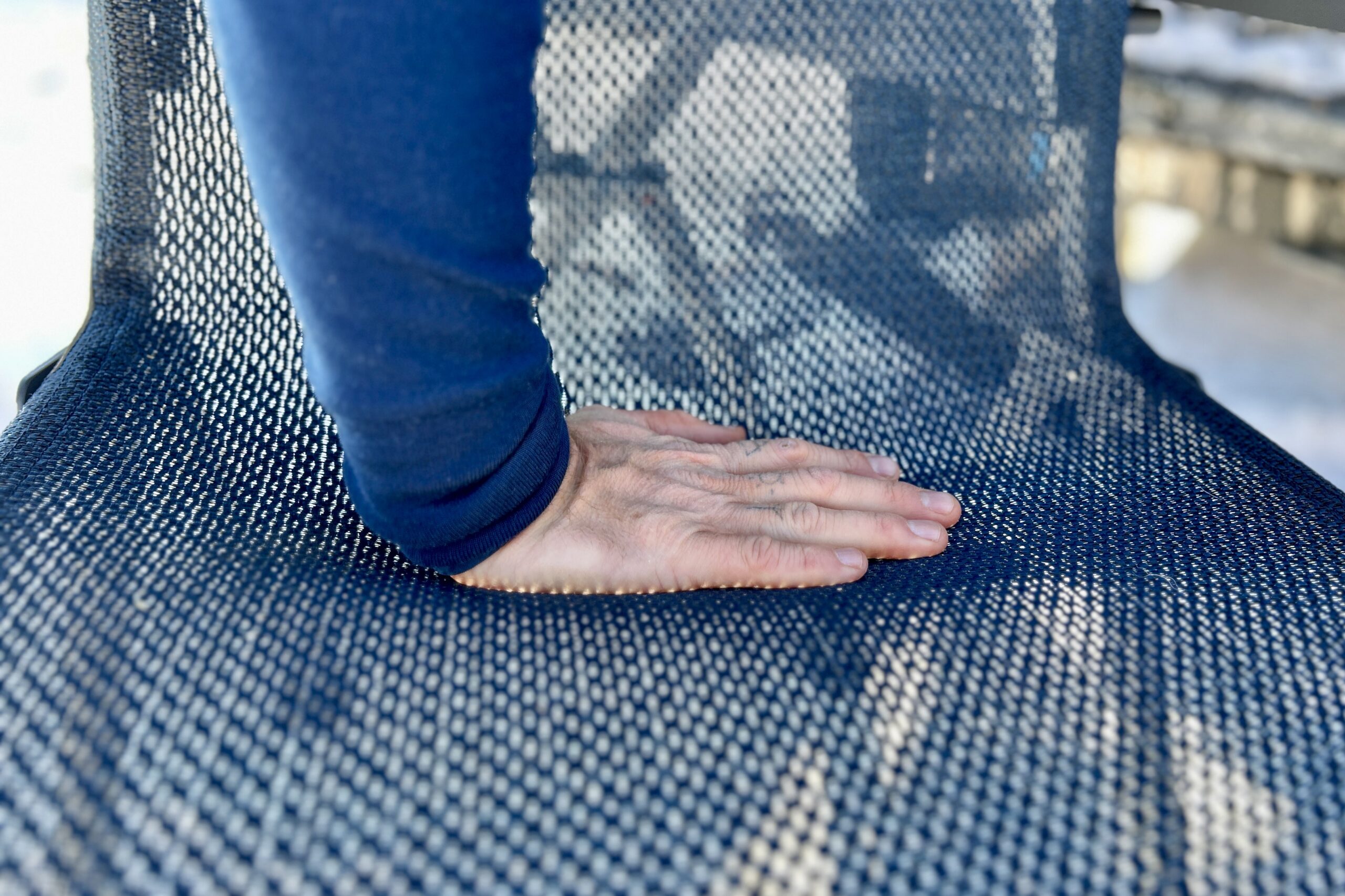 A person pushes their hand into the mesh of a camping chair.