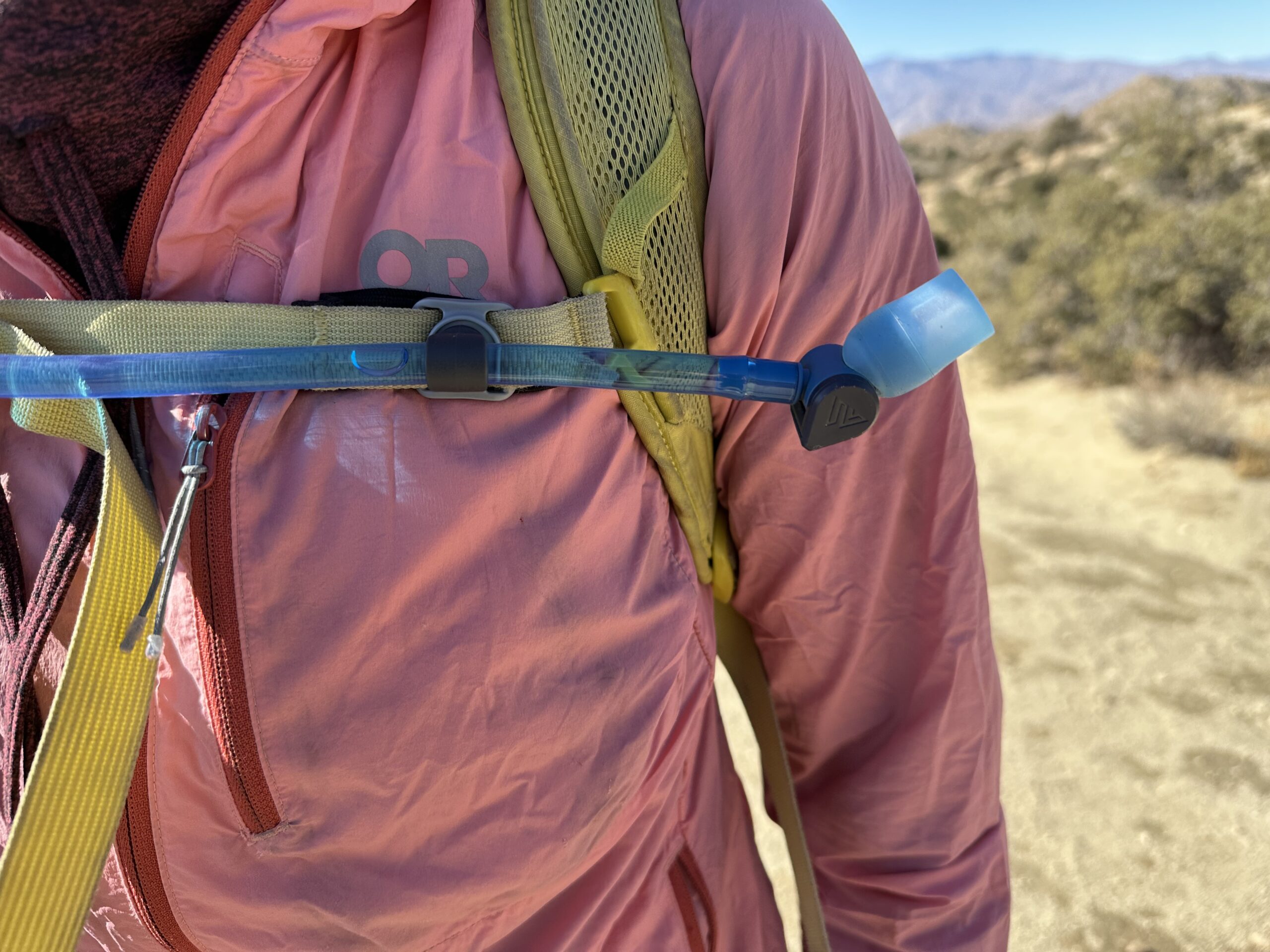 Close up image of the hydration hose attached to the backpack's sternum strap with a magnet.