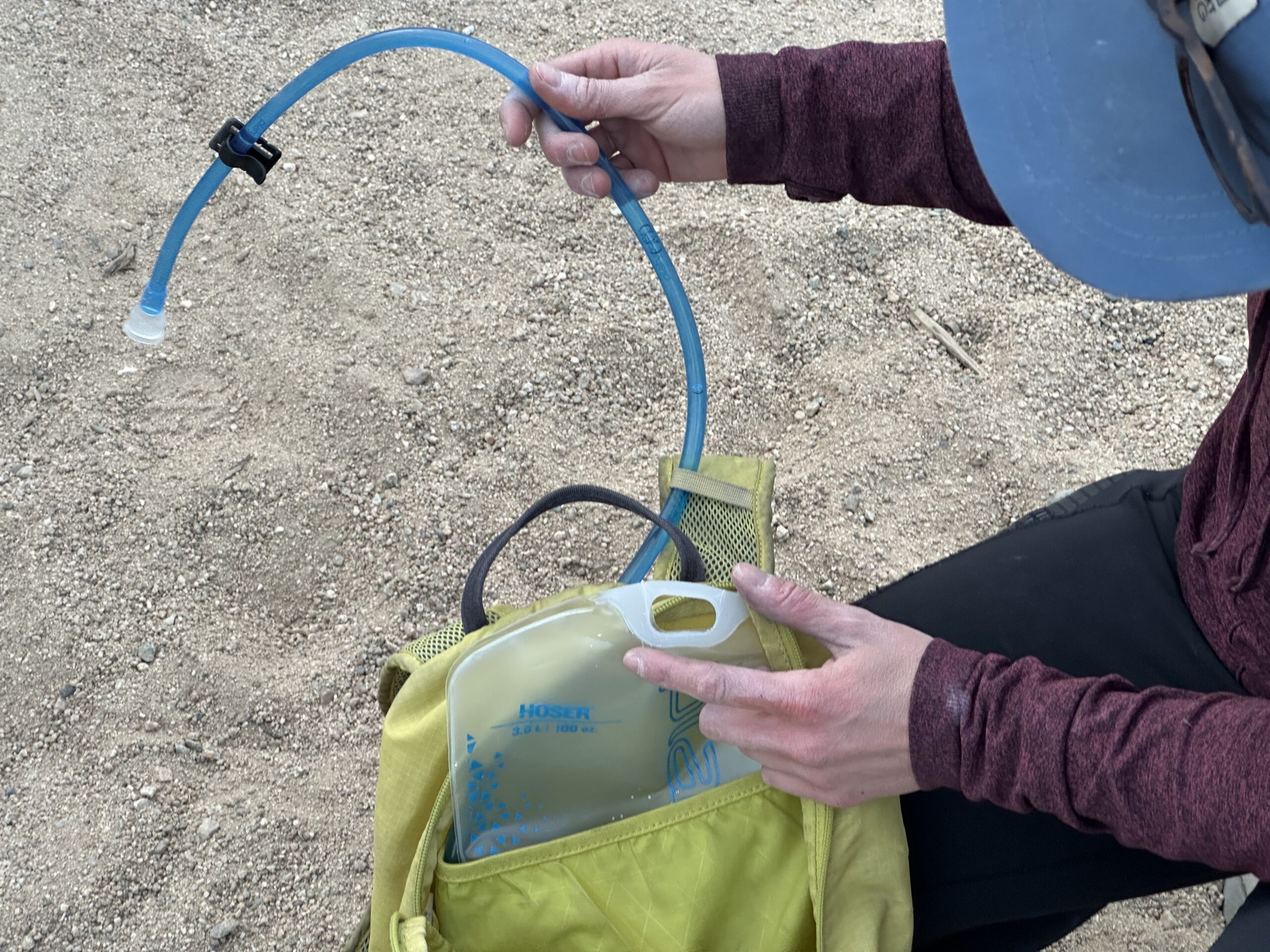 Close up photo of a hiker showing how the Platypus Hoser's hose threads through her backpack.
