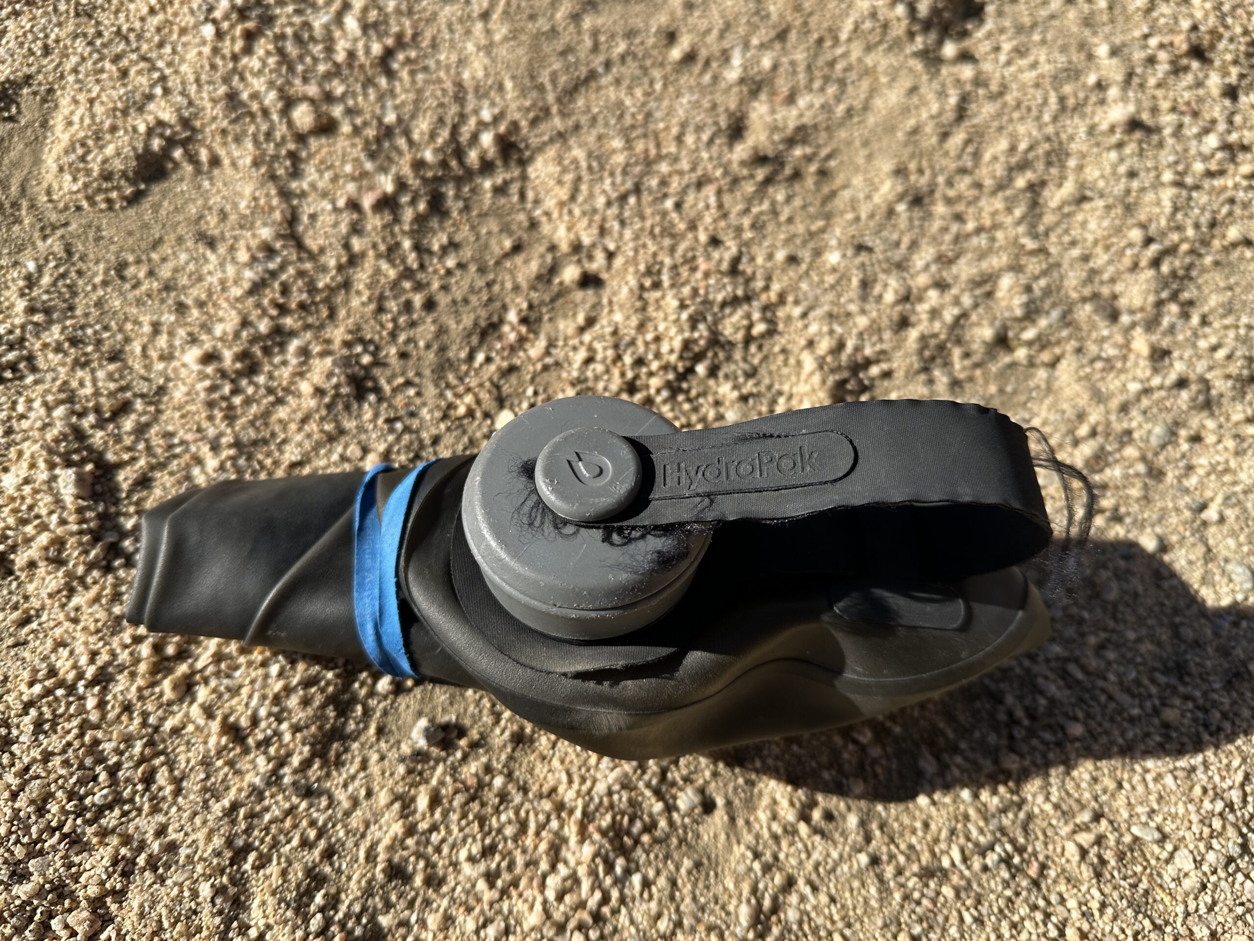 A close up photo shows the HydraPak Seeker water bag rolled up and secured with a rubber band.