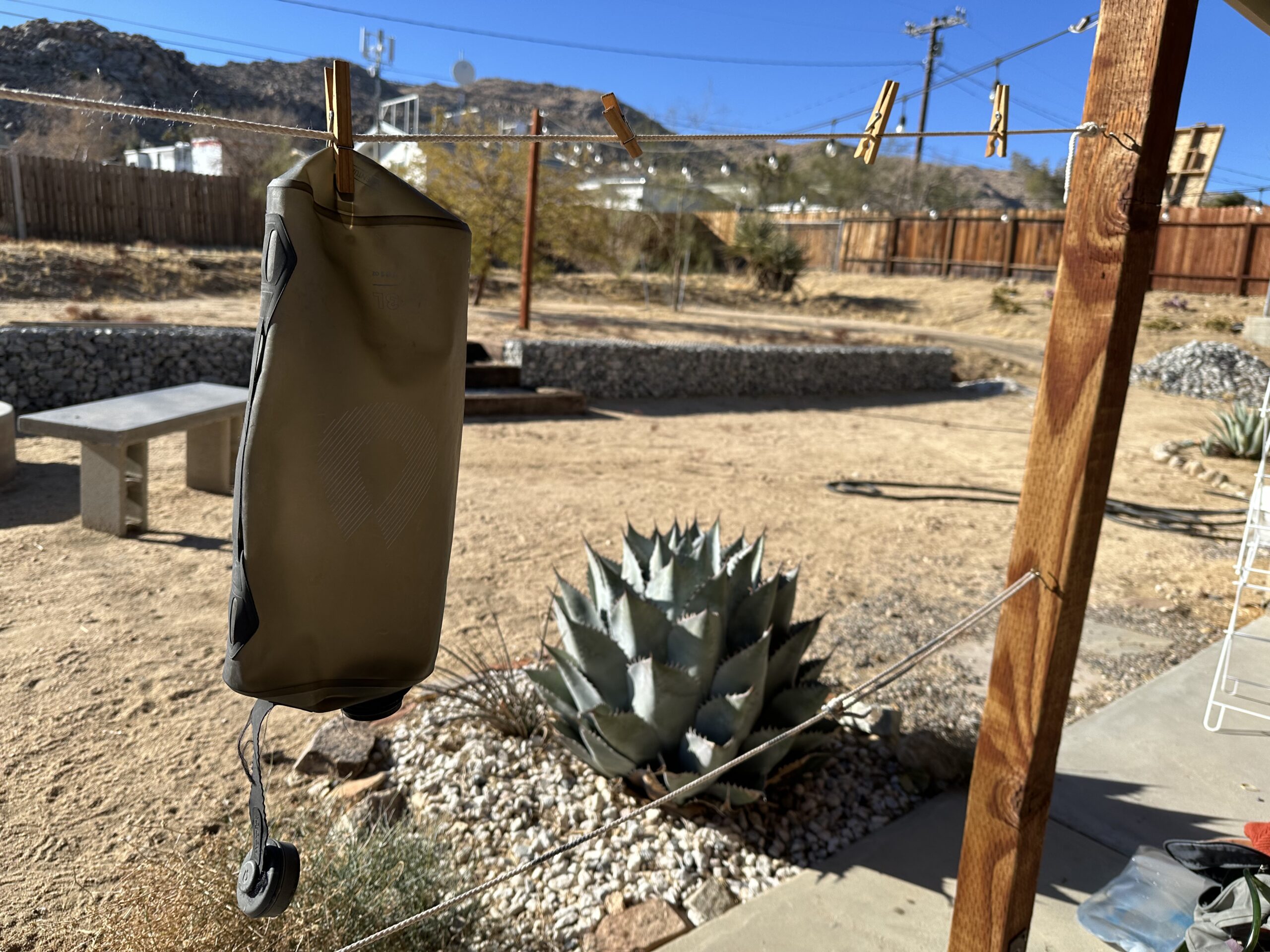 The HydraPak Seeker water bag is shown hanging to dry on a clothesline. The background is a desert backyard.