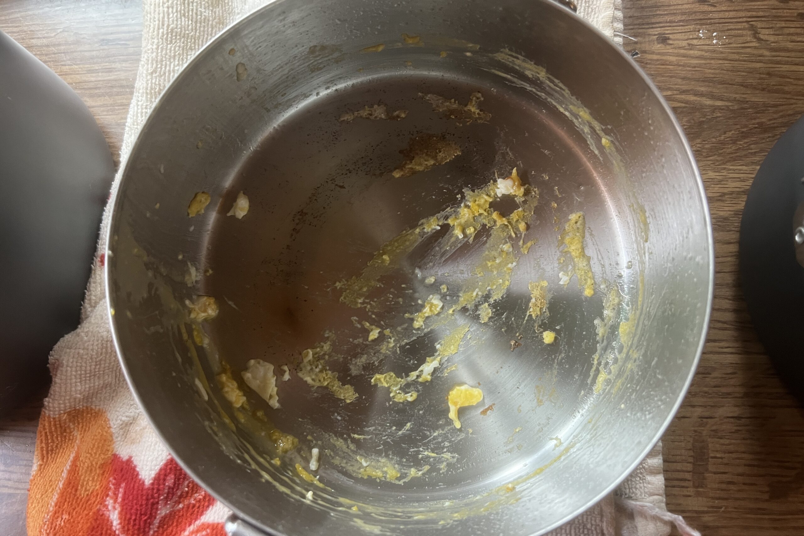 A top down view of a steel pot with egg remnants.