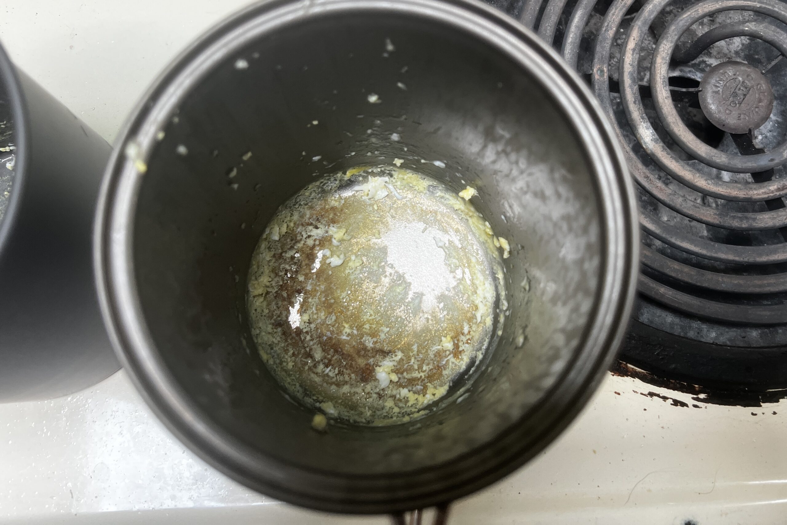 A top down view of a pot with burned egg on the bottom.